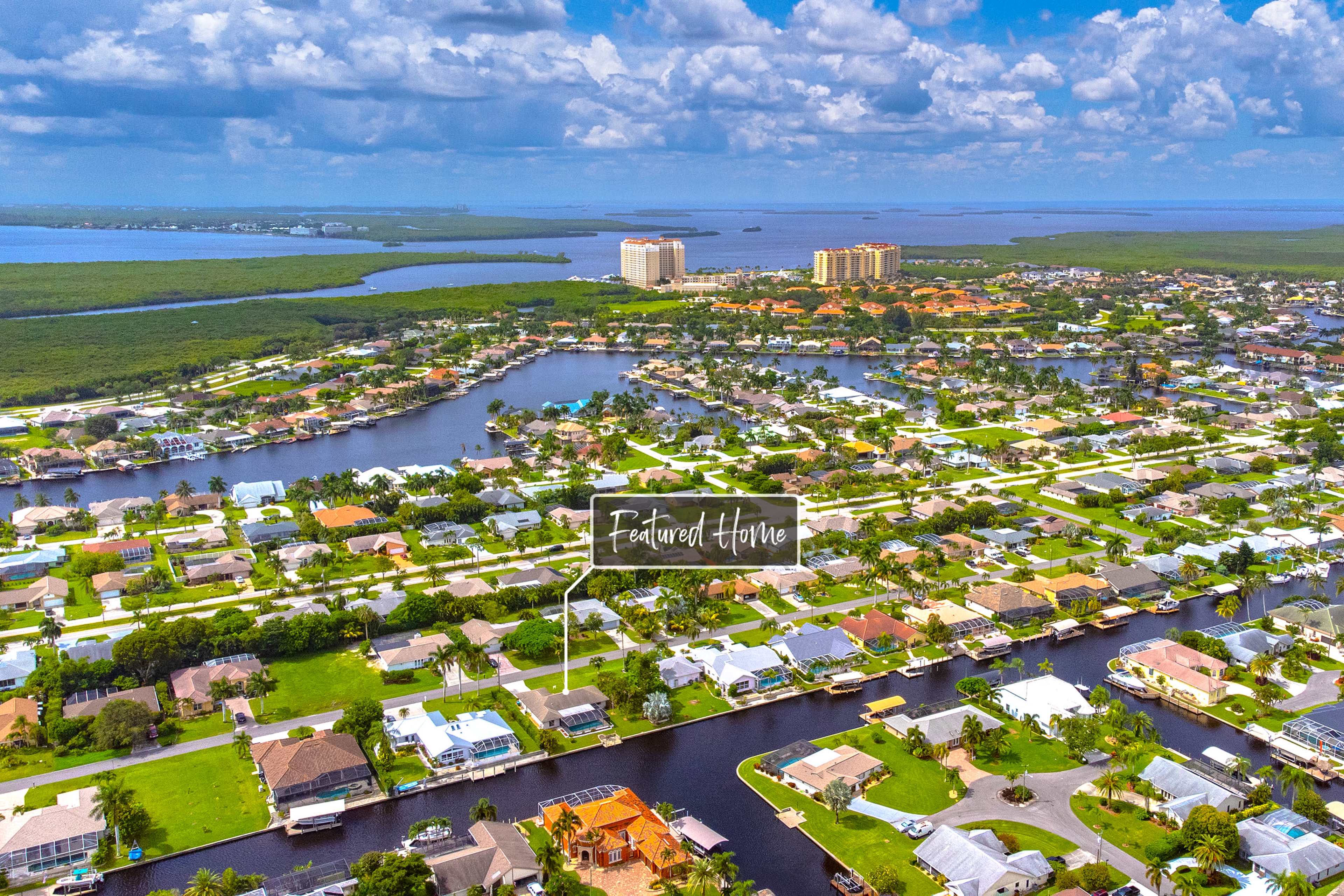 An aerial view of a residential neighborhood with houses lining waterways and a marked featured home.