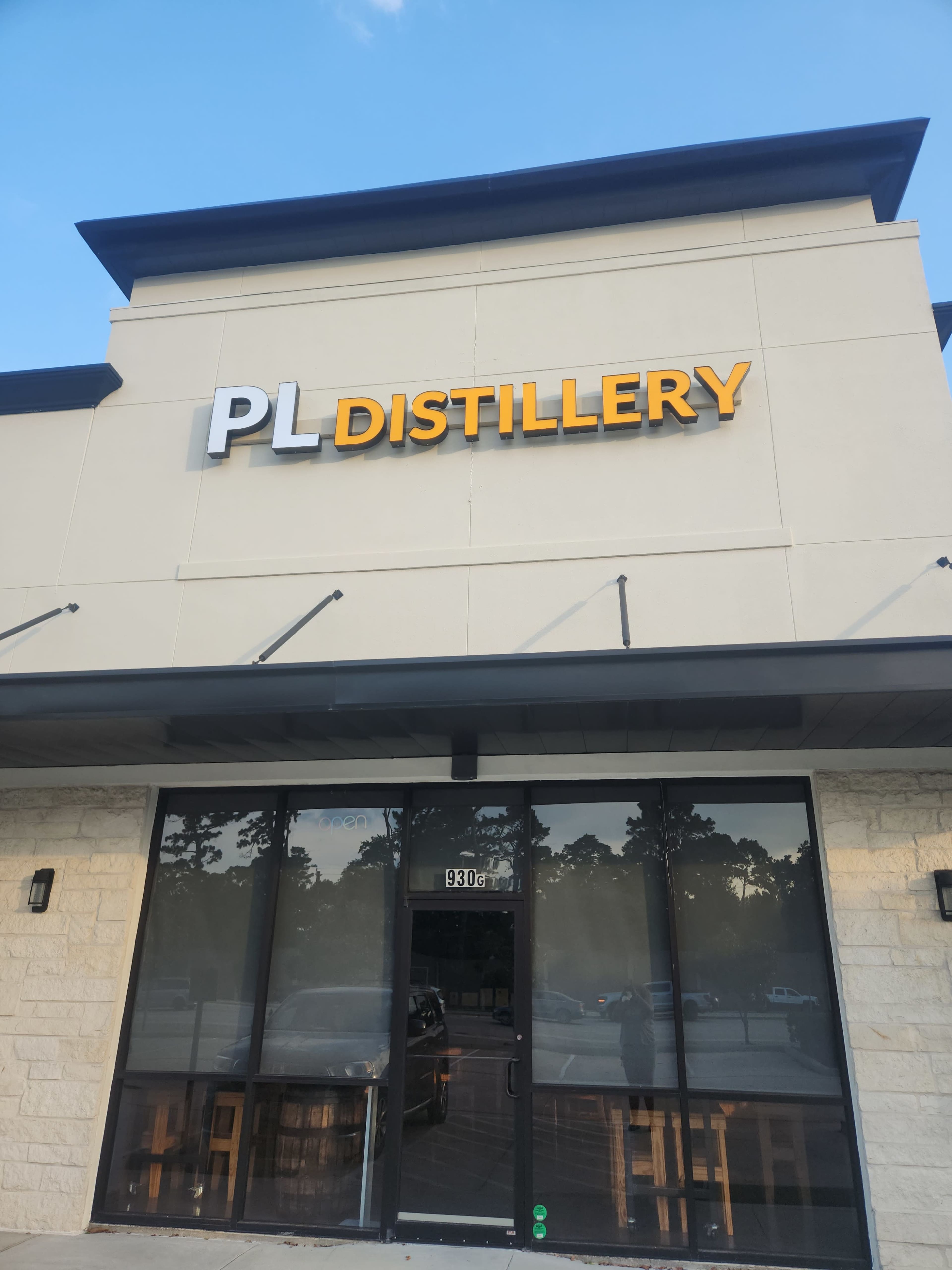 The image shows the exterior of a building with a sign that reads "PL DISTILLERY" above the entrance.