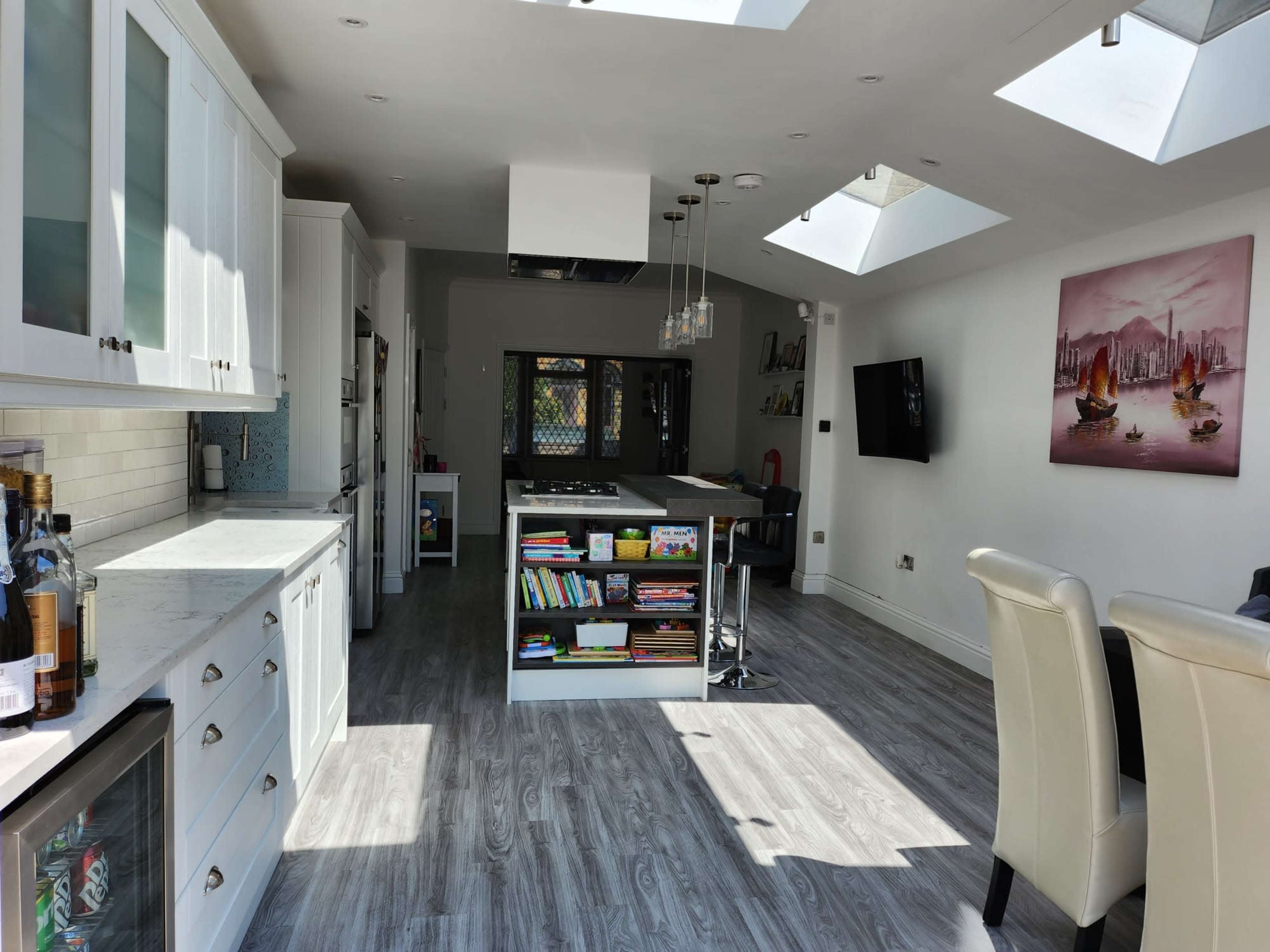 A spacious kitchen features modern cabinetry, a central island, and large skylights providing natural light.