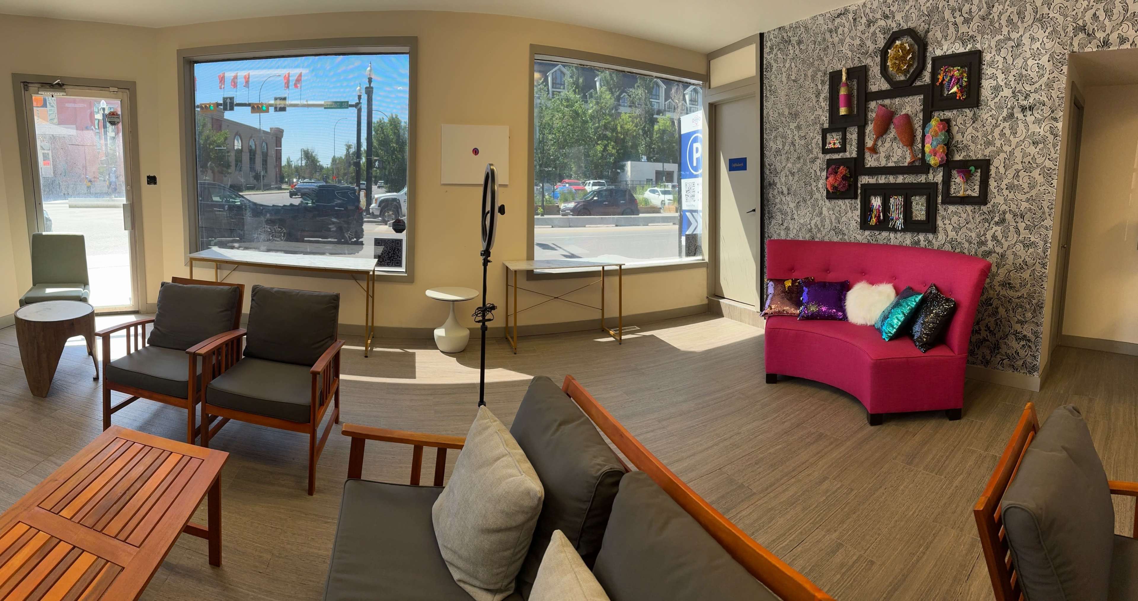The interior of a modern lounge features a mix of stylish seating, decorative wall art, and large windows providing a view of the street outside.