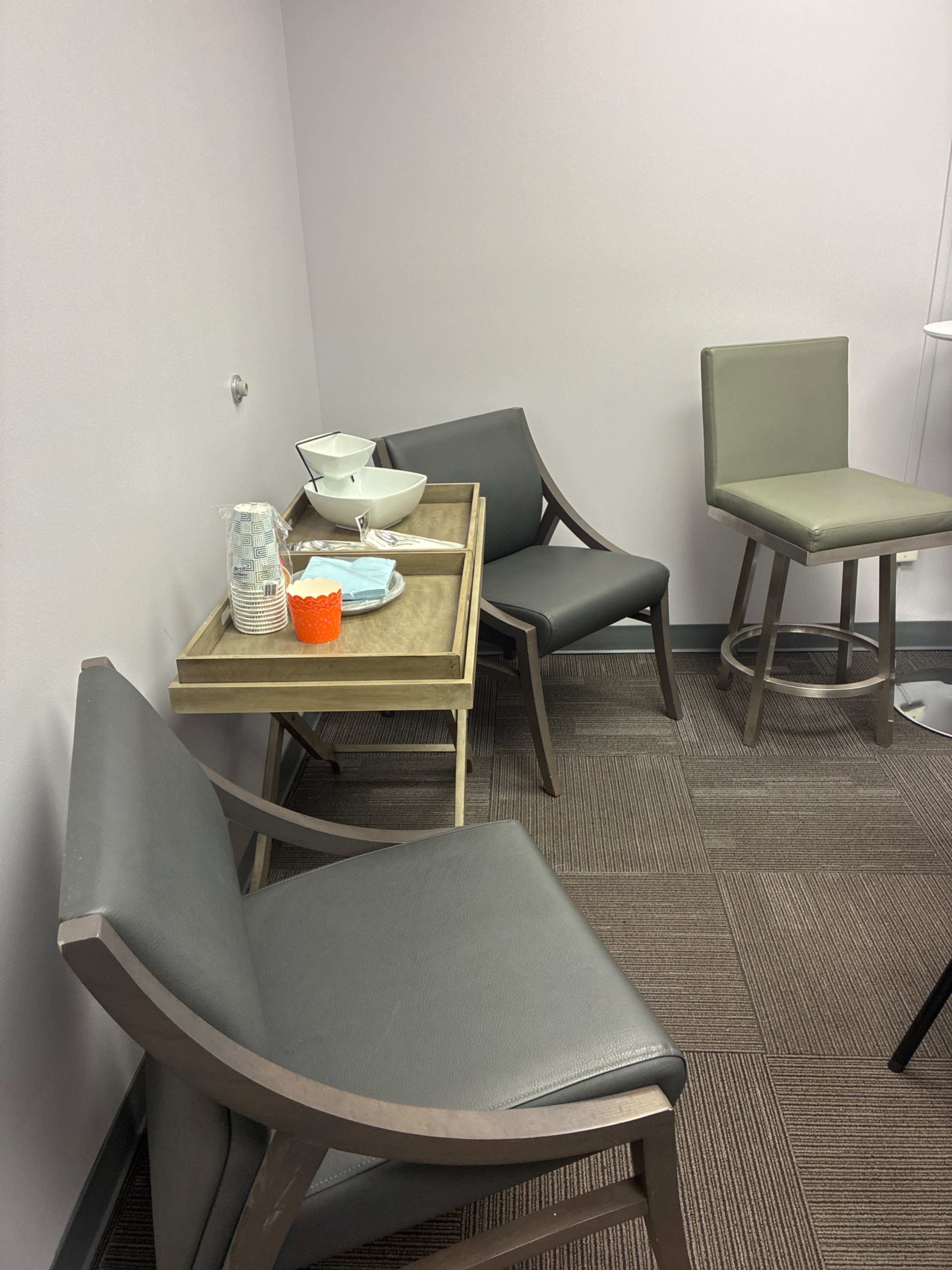 The image shows a corner of a room with two chairs positioned around a small table that holds bowls and cups.