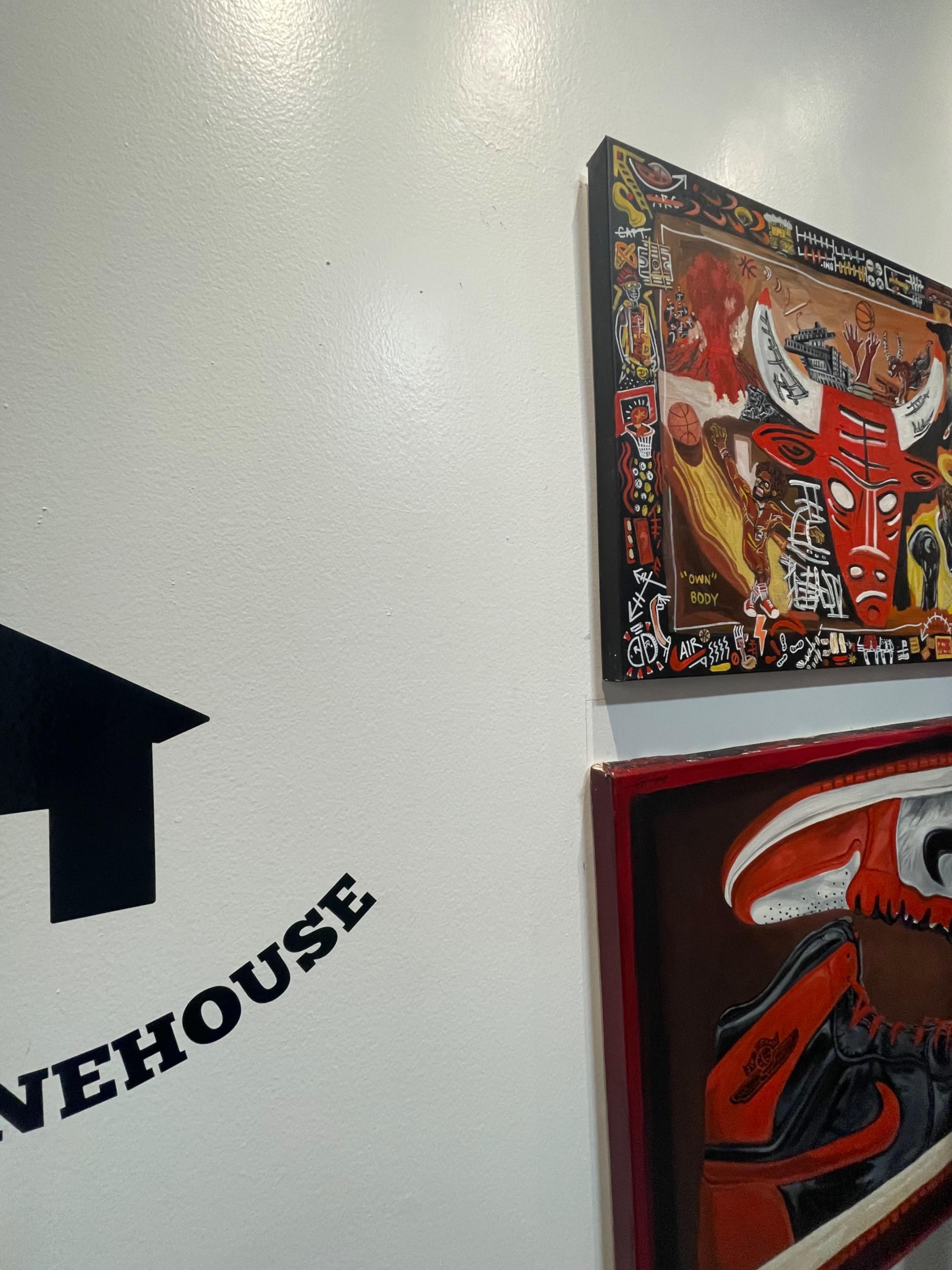 A wall with a black arrow pointing left, alongside two framed artworks featuring vibrant colors and designs.