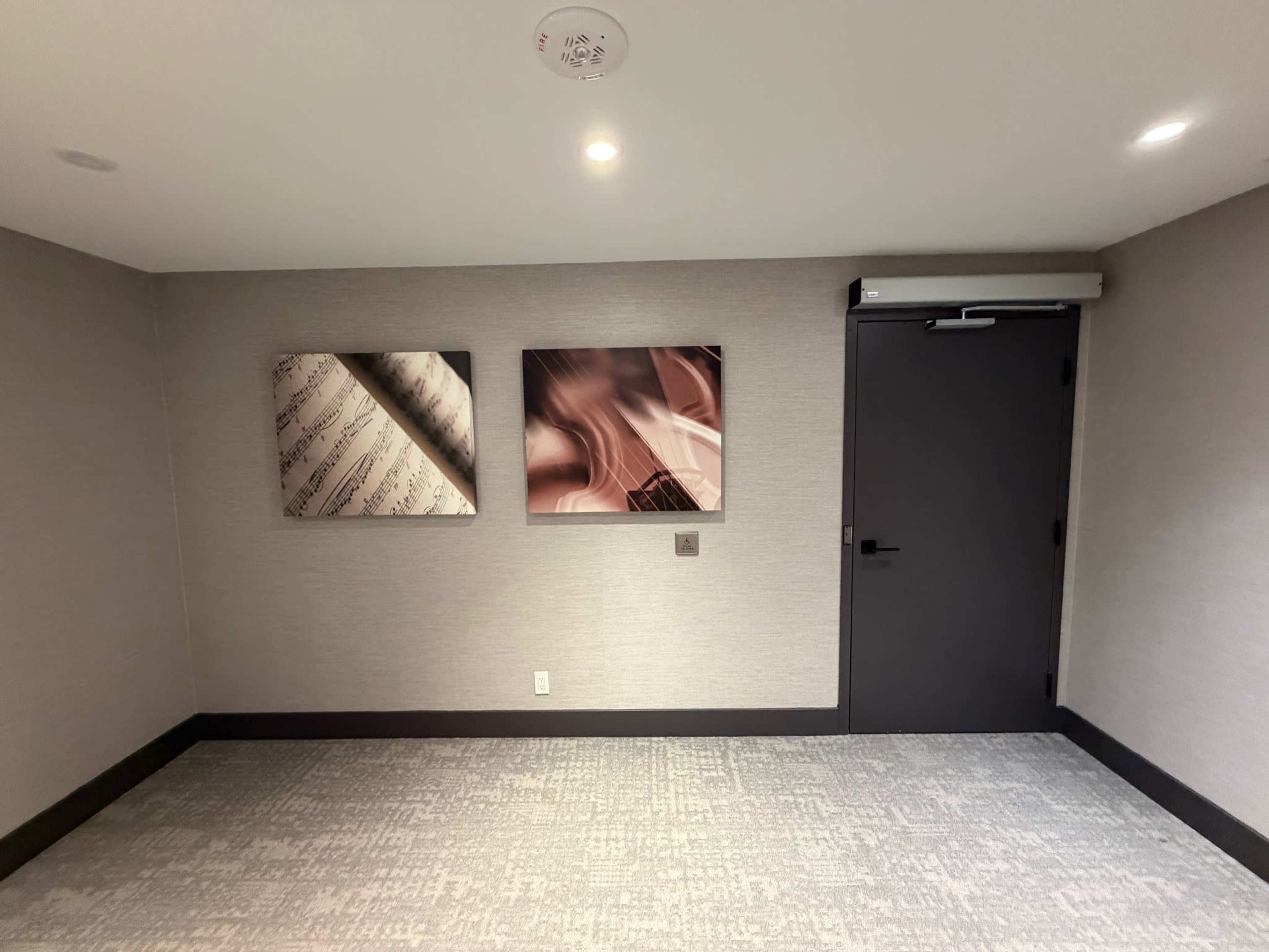 The image shows a room with two framed artworks on the wall and a closed door to the right.