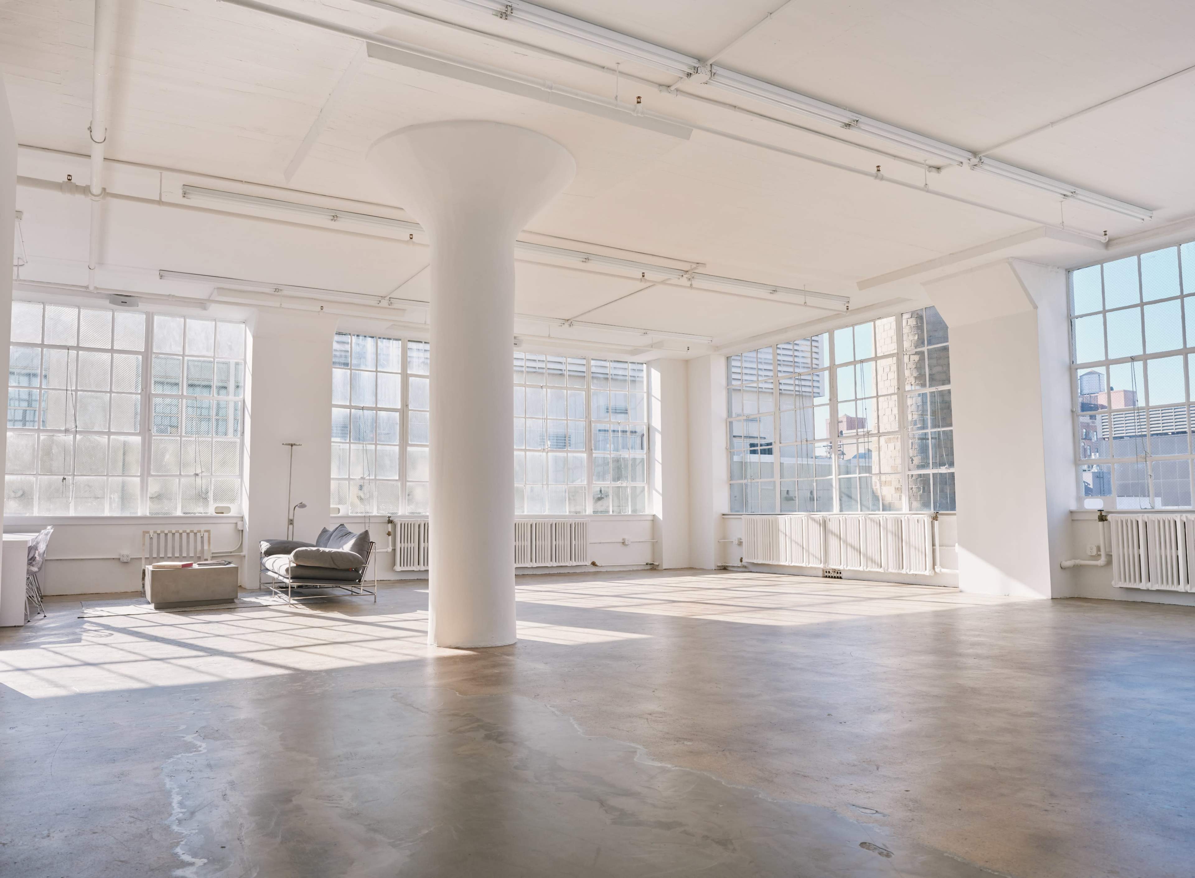 A spacious, well-lit interior features large windows and a concrete floor.