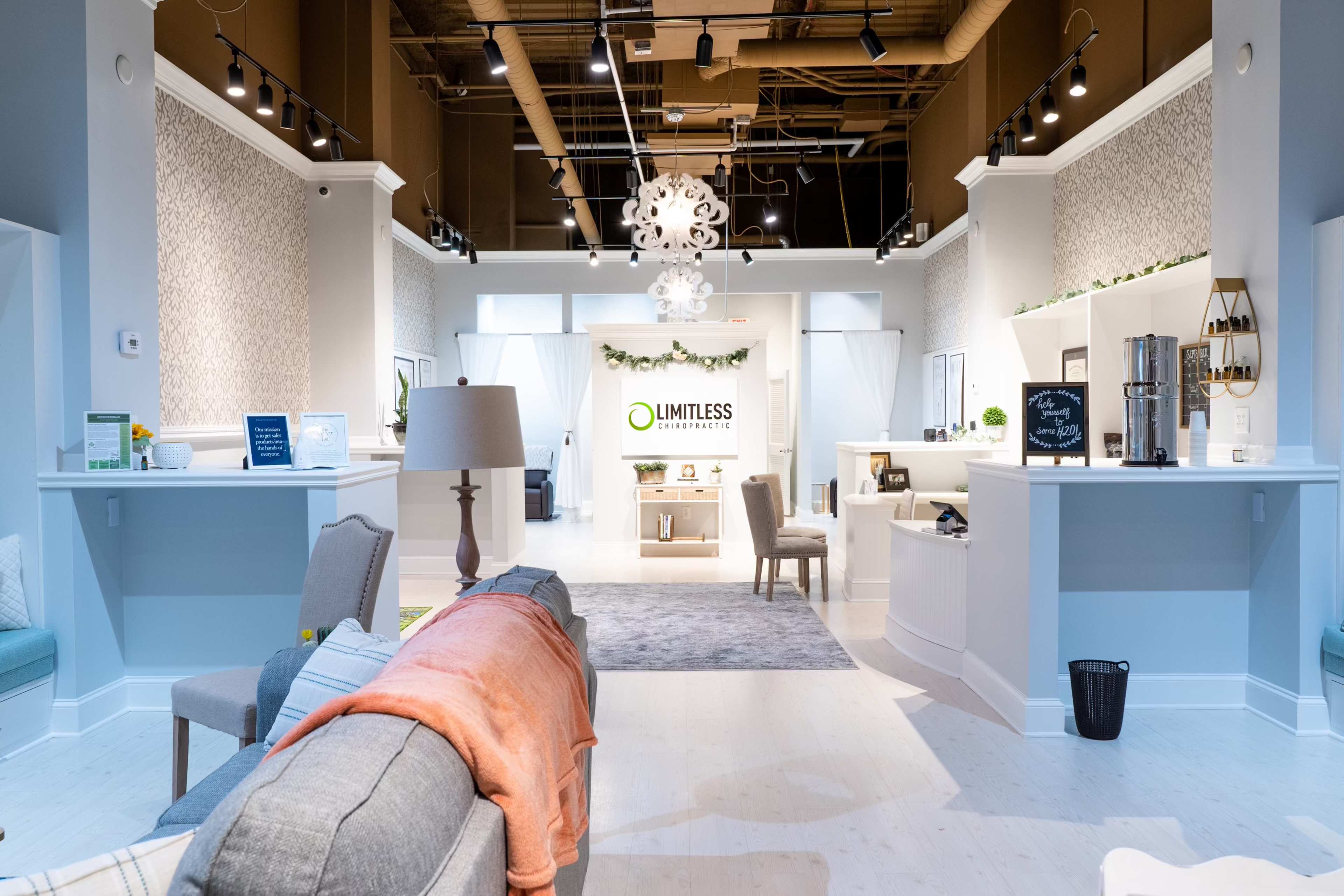 A modern interior design studio with white walls, a gray sofa, and a central display area featuring the logo "LIMITLESS" against a backdrop of decorative elements.