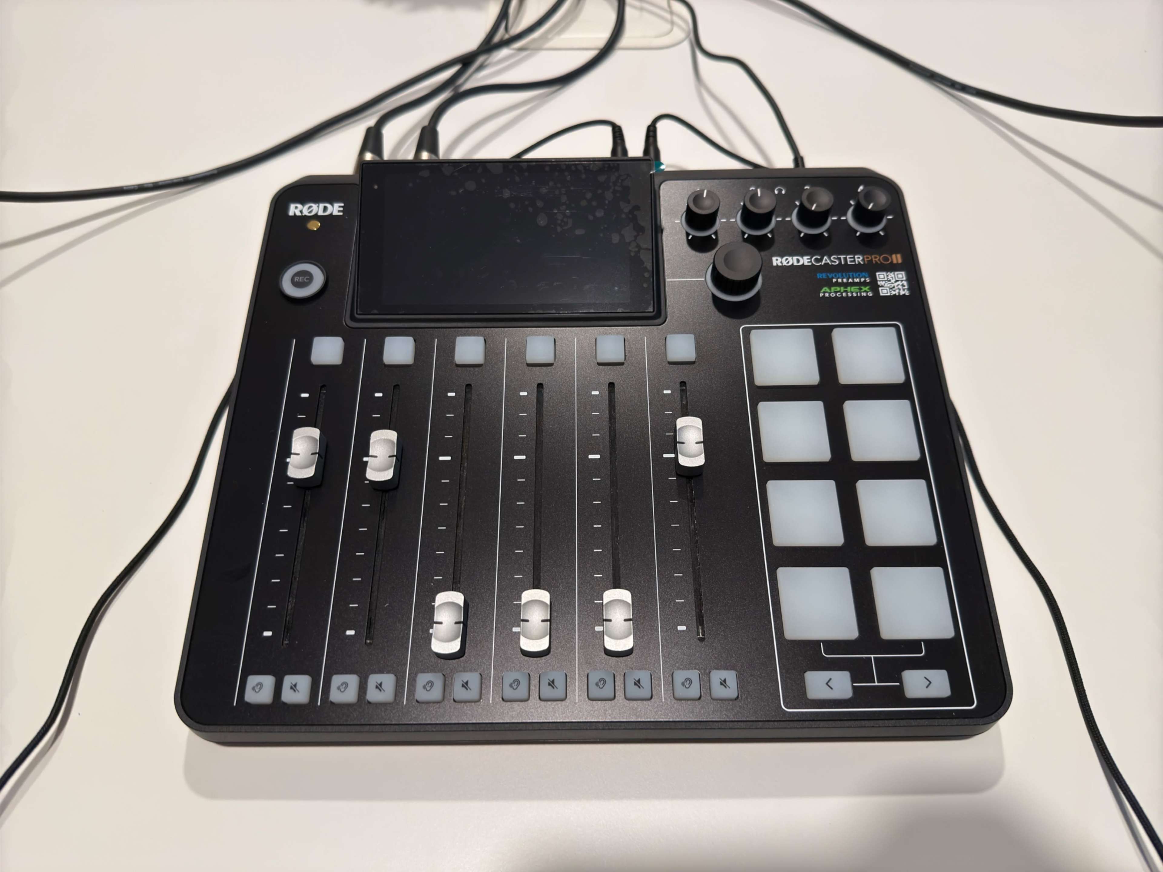 The image shows a Rodecaster Pro audio mixing console with sliders, buttons, and a display screen.