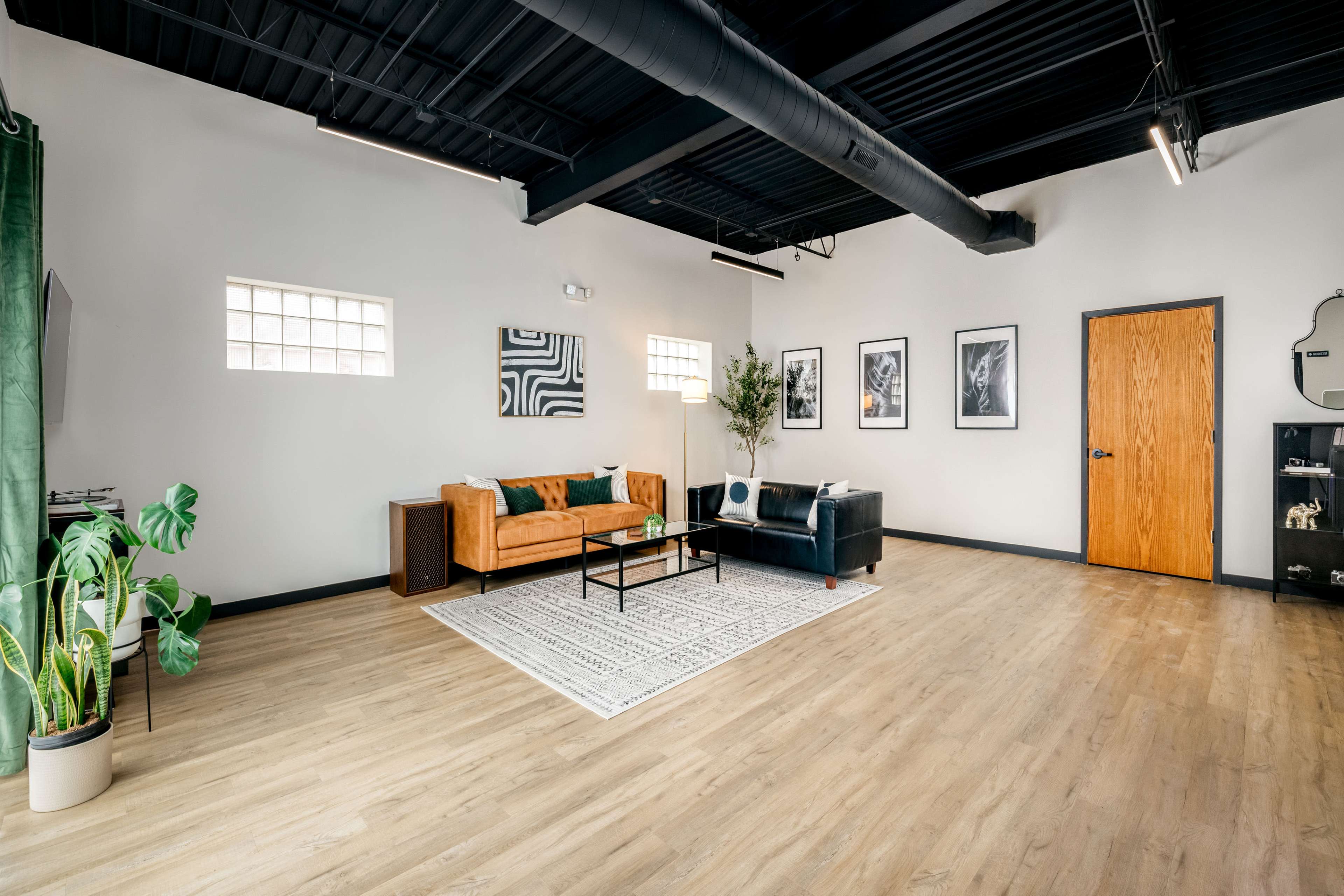 A spacious living area with a tan sofa, a black chair, a central coffee table, and framed artwork on the walls.