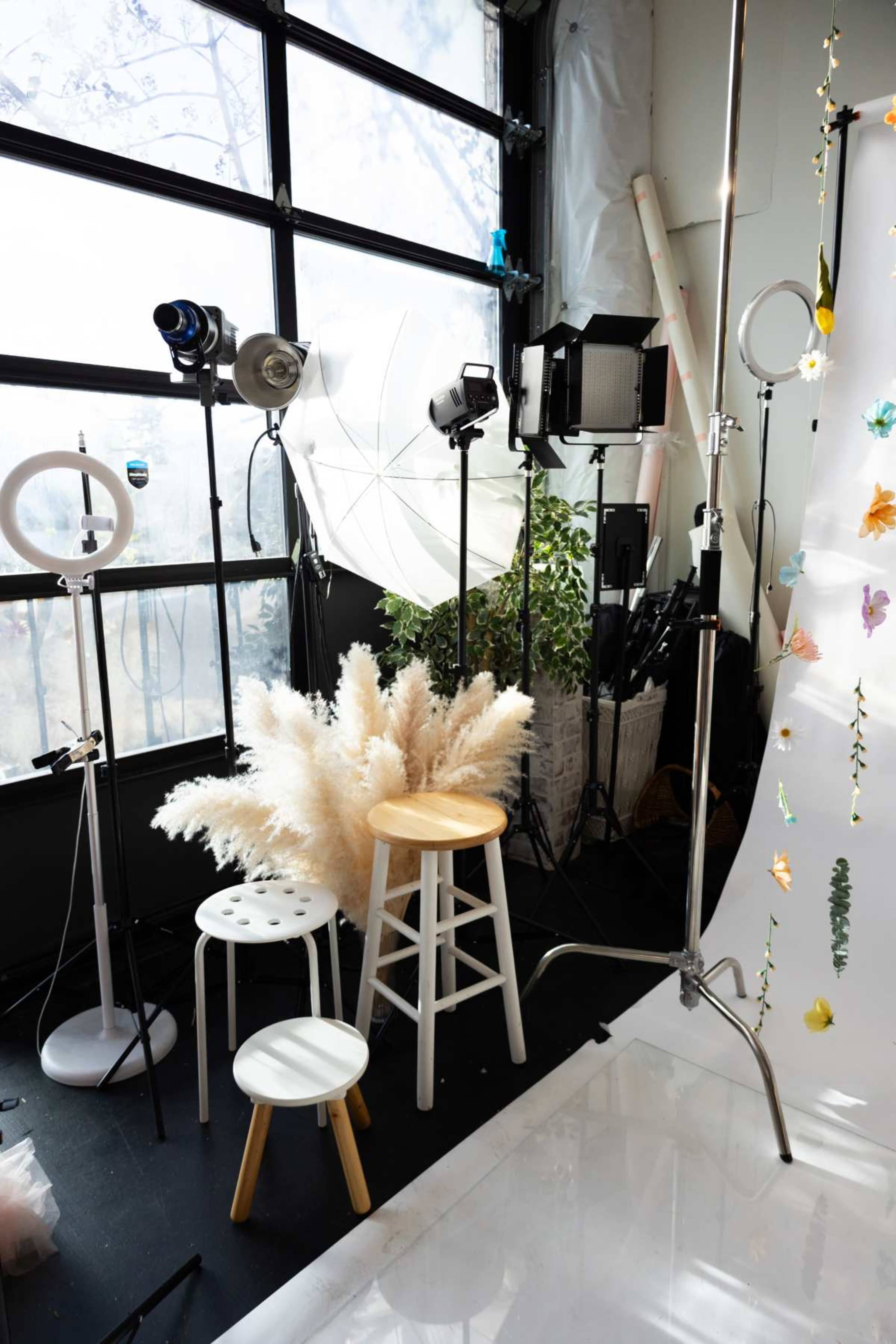 The image shows a photography studio setup featuring various lighting equipment, props, and a backdrop.