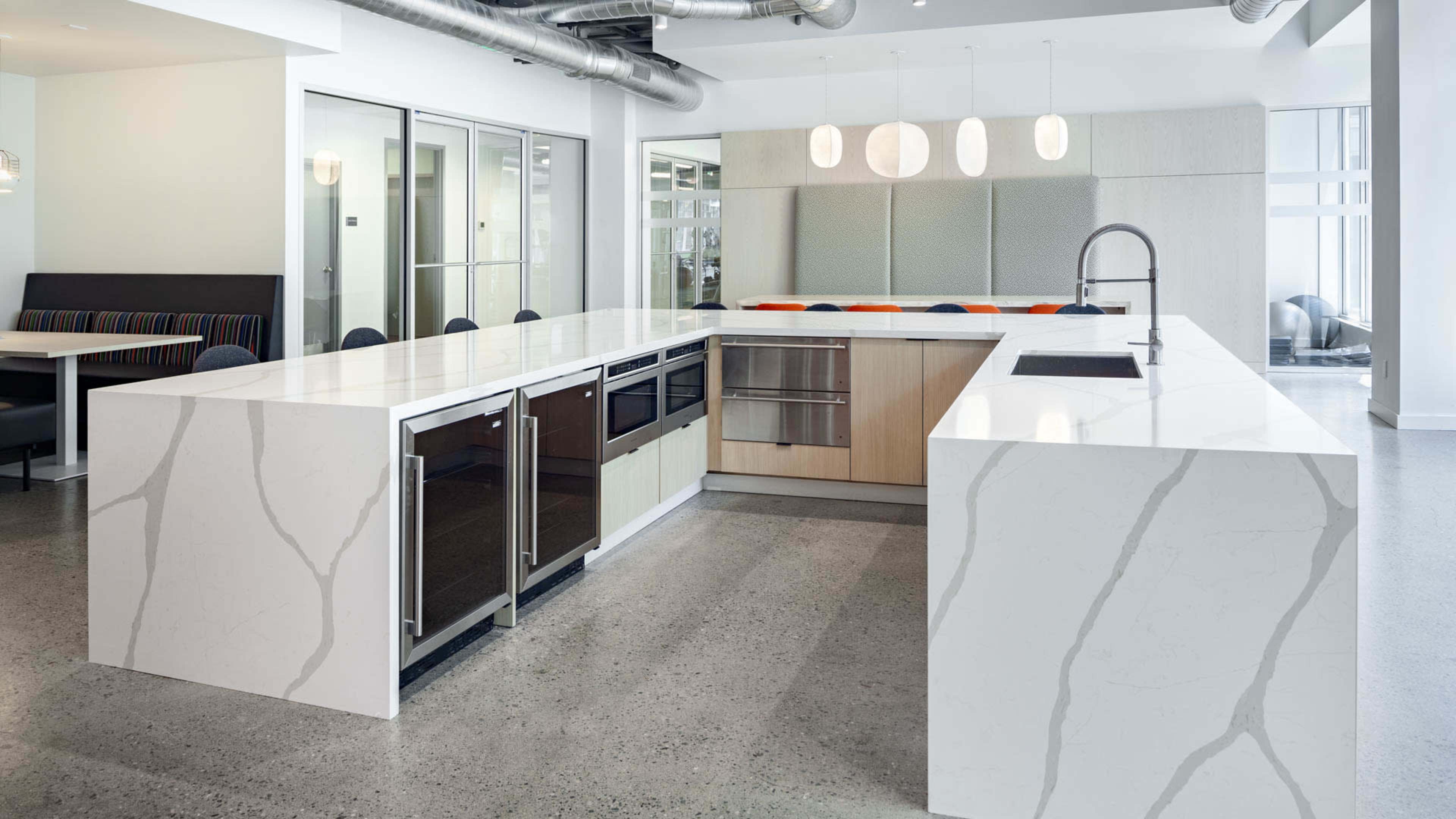 A modern kitchen with a large island, equipped with sleek cabinetry, a sink, and stainless steel appliances.