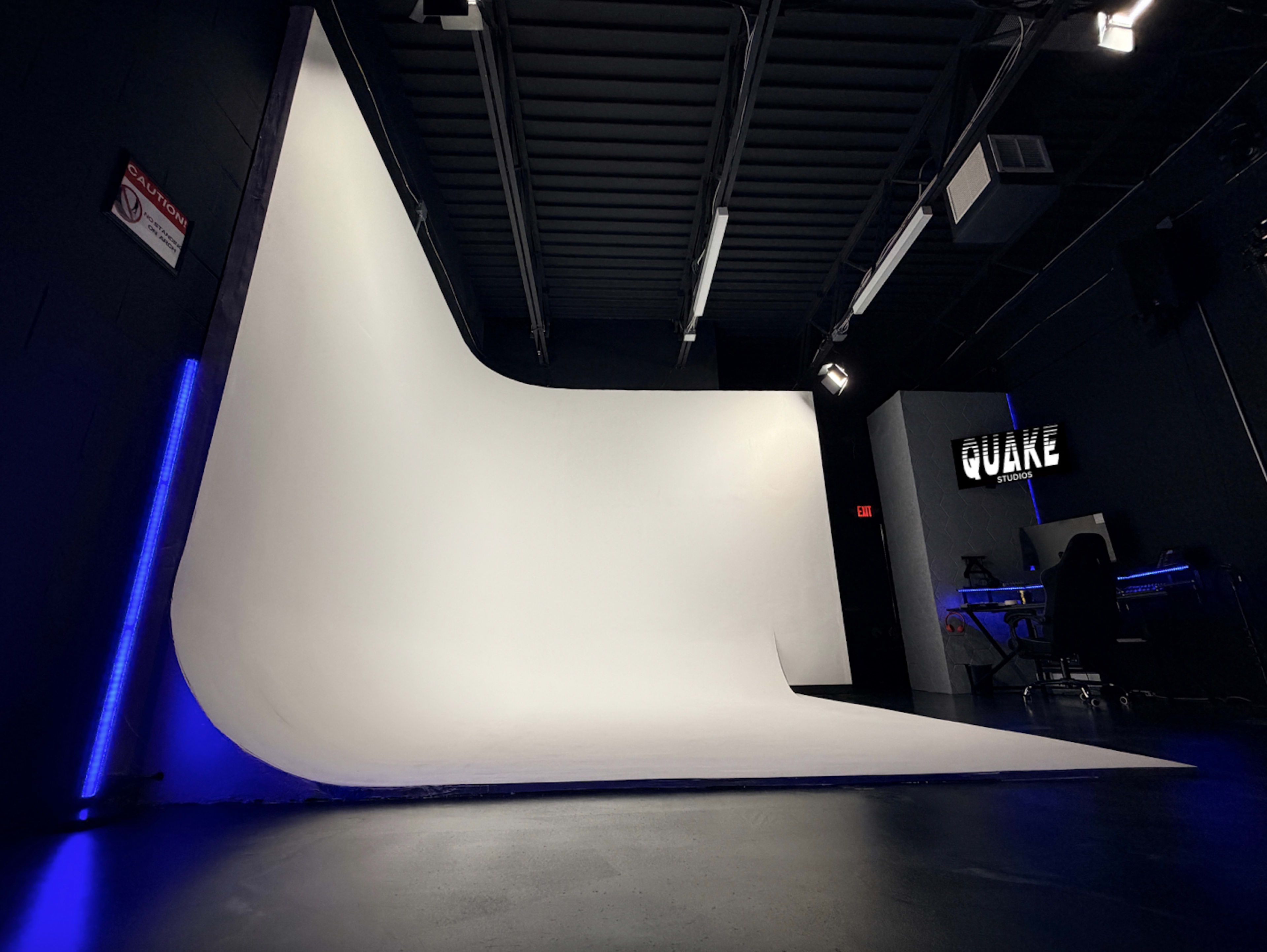 The image shows a spacious, well-lit studio with a large white backdrop and a dark wall featuring the word "SQUARE" illuminated in light.