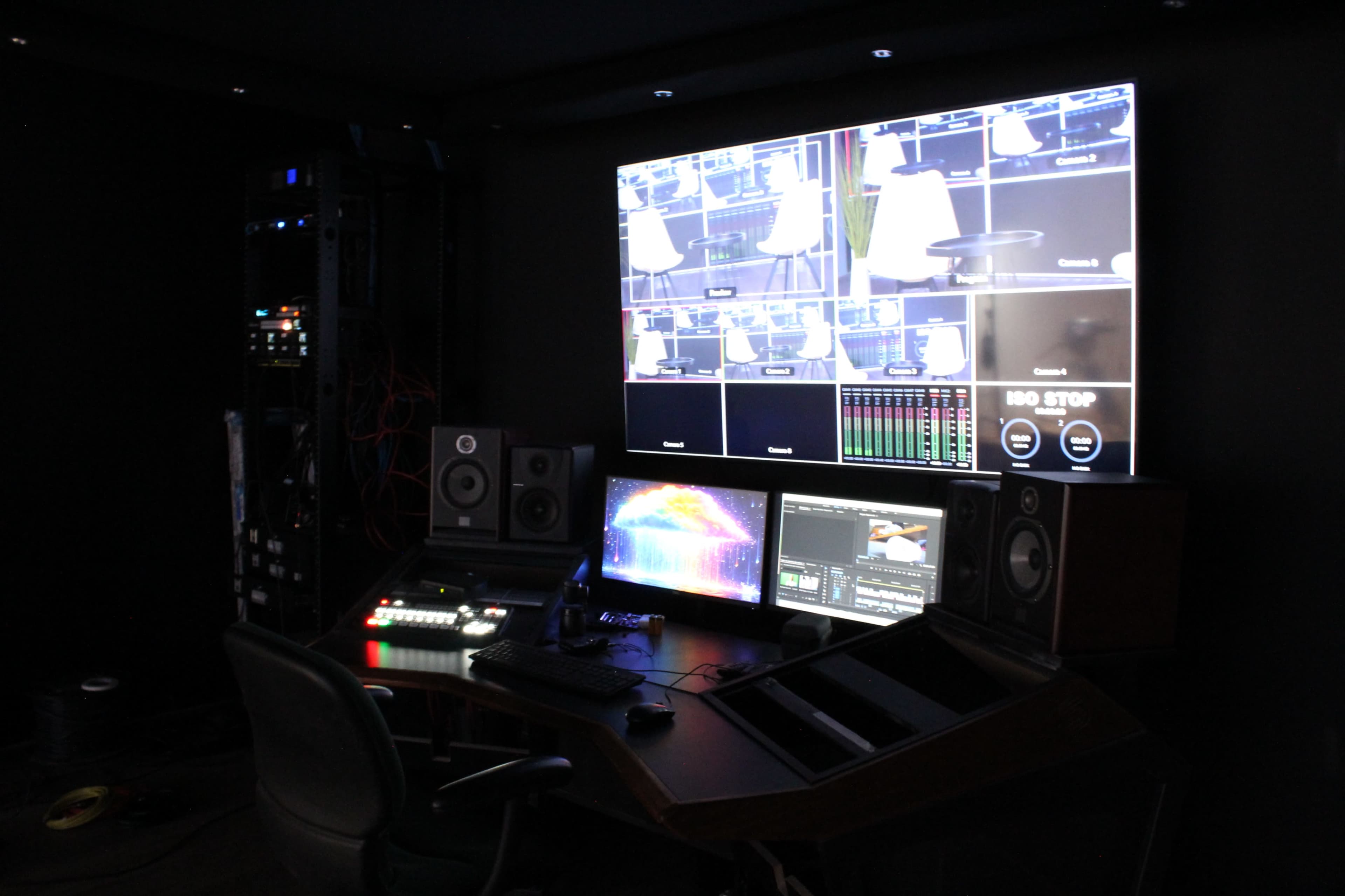 The image shows a control room with multiple monitors, audio equipment, and a large display showcasing various feeds.