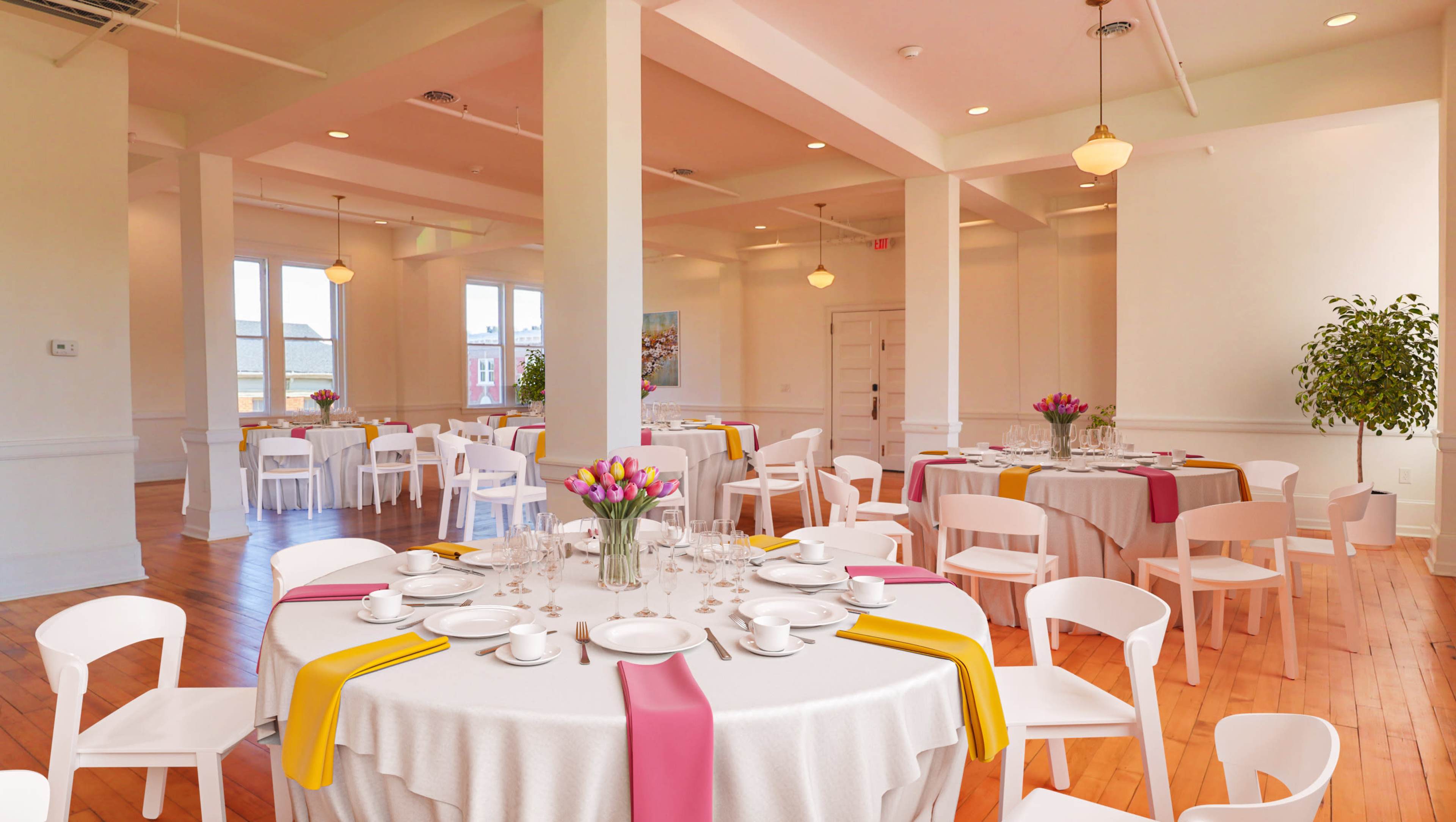 A bright, modern dining room features round tables covered with beige tablecloths, adorned with colored runners and floral centerpieces, surrounded by white chairs.