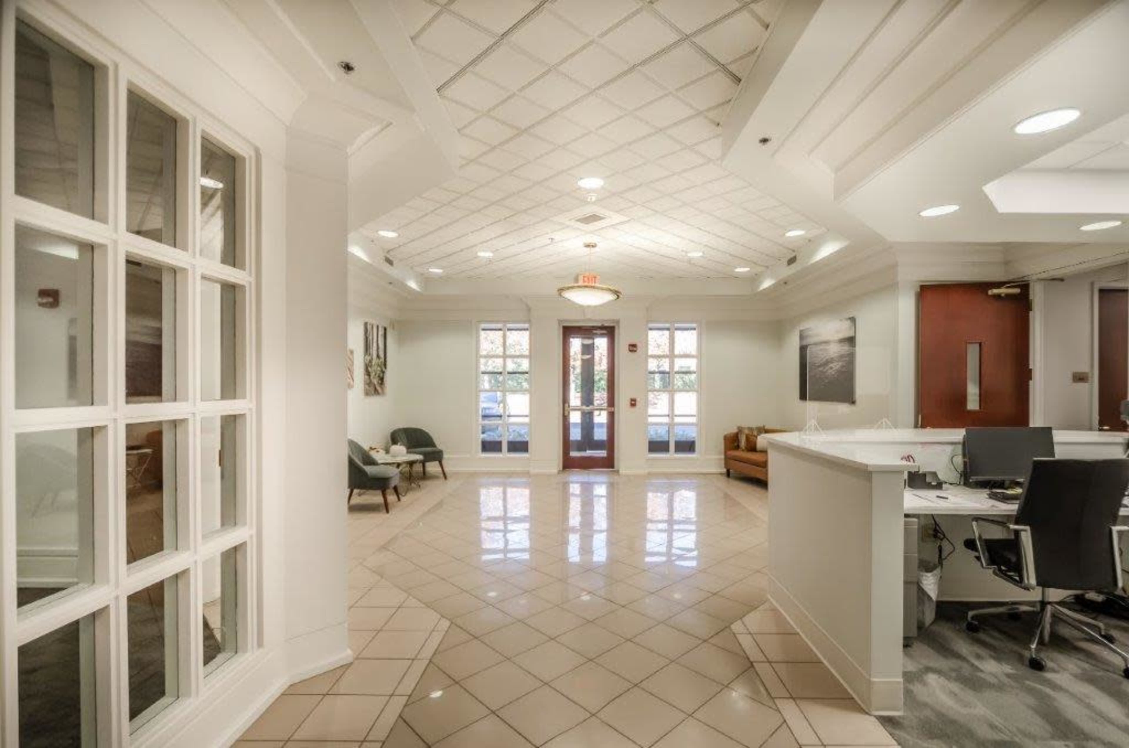 A bright, spacious lobby area with a reception desk, seating areas, and large windows.