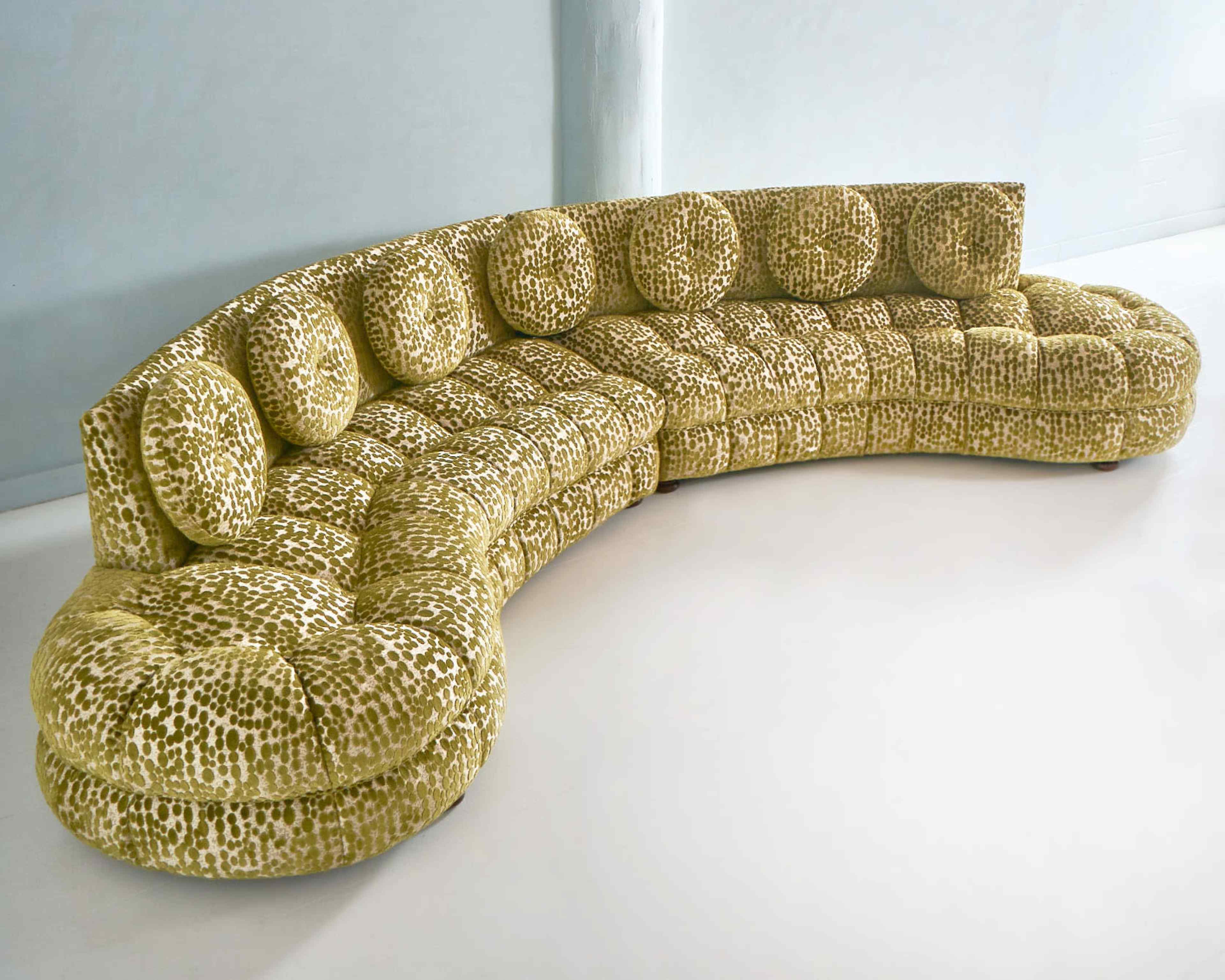 The image shows a curved, tufted sectional sofa in a green and yellow pattern.