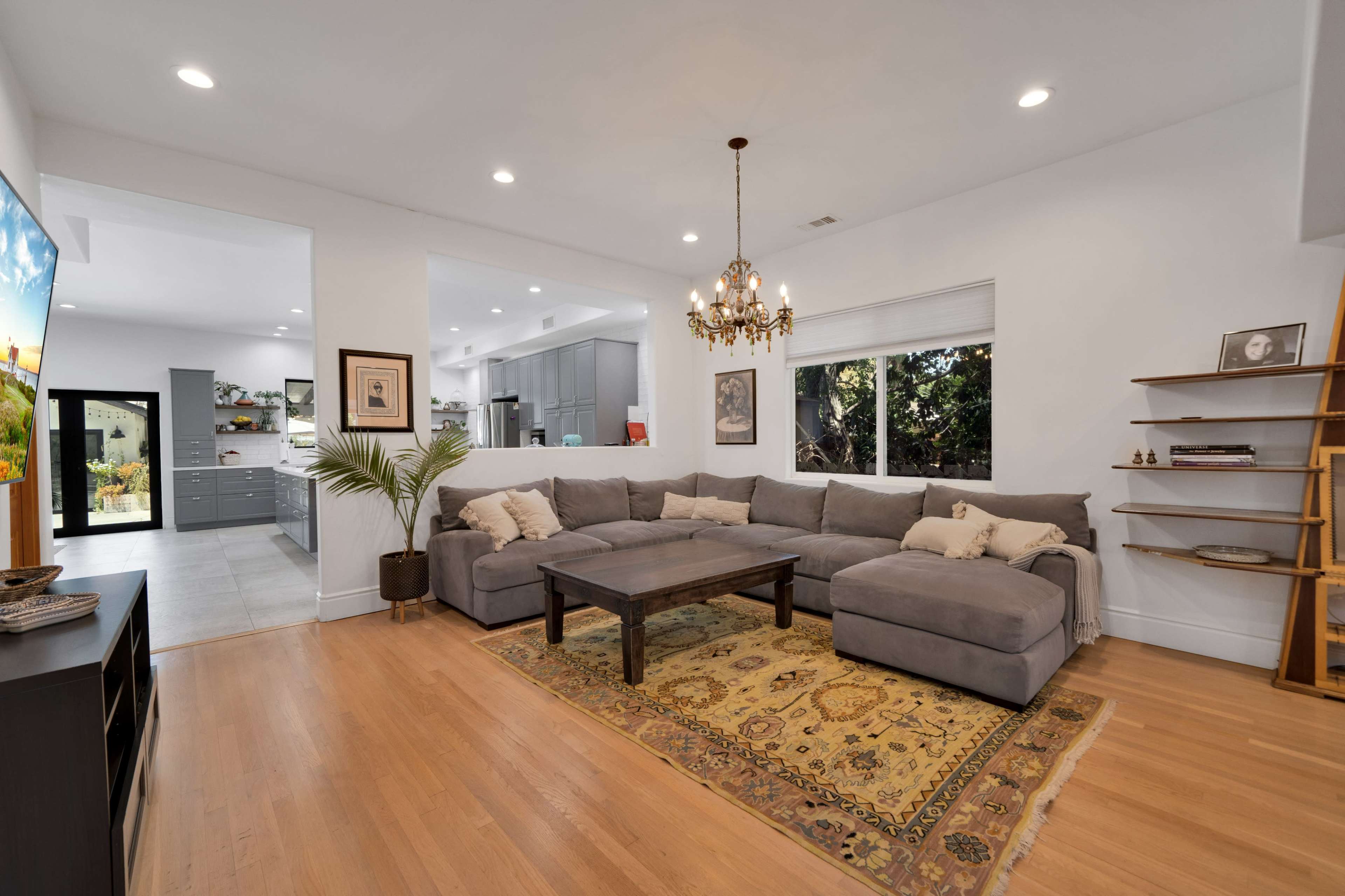 The image shows a modern living room featuring a large gray sectional sofa, a wooden coffee table, and a decorative area rug.