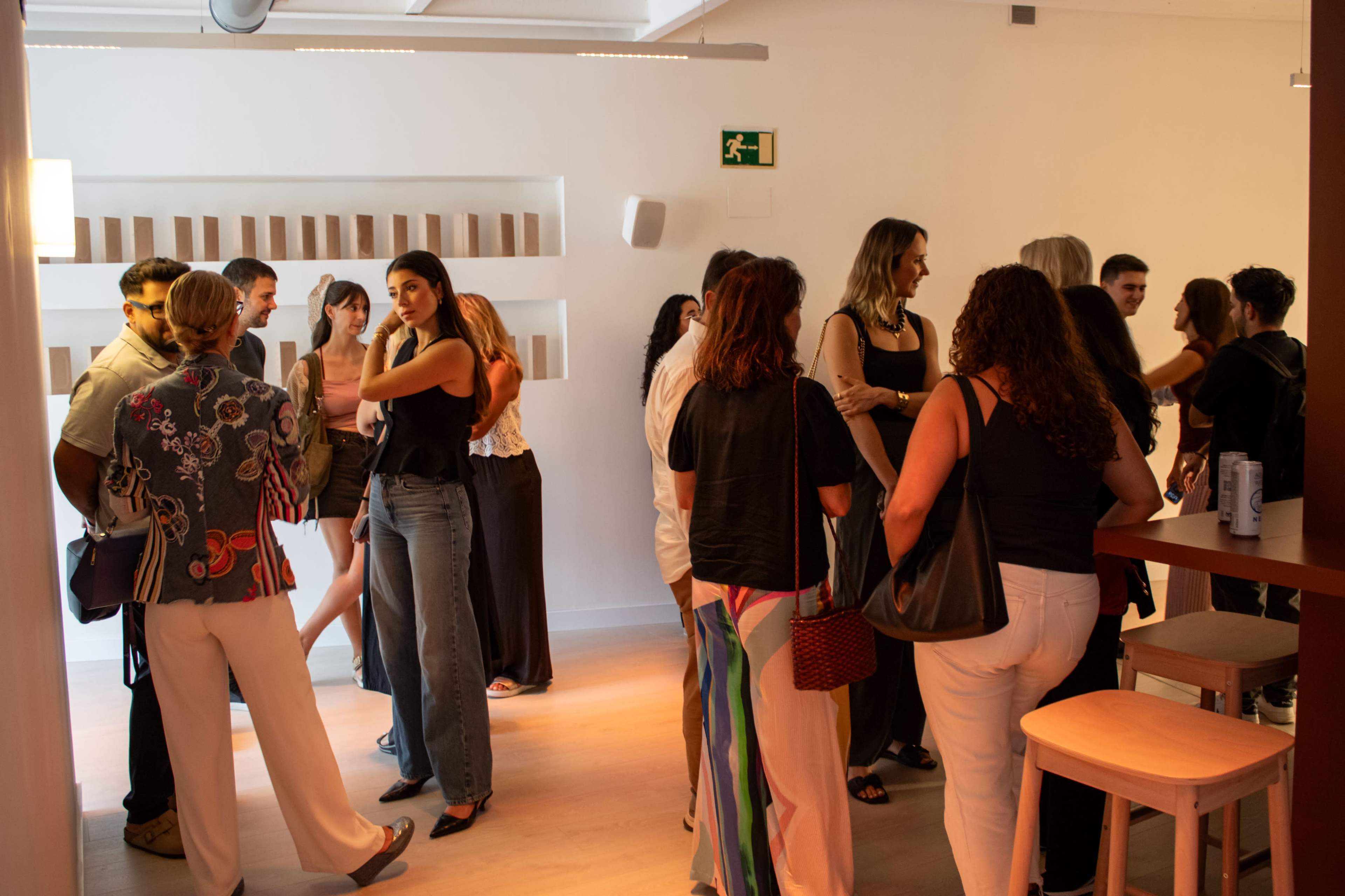 A group of people are engaged in conversation in a modern, well-lit interior space.