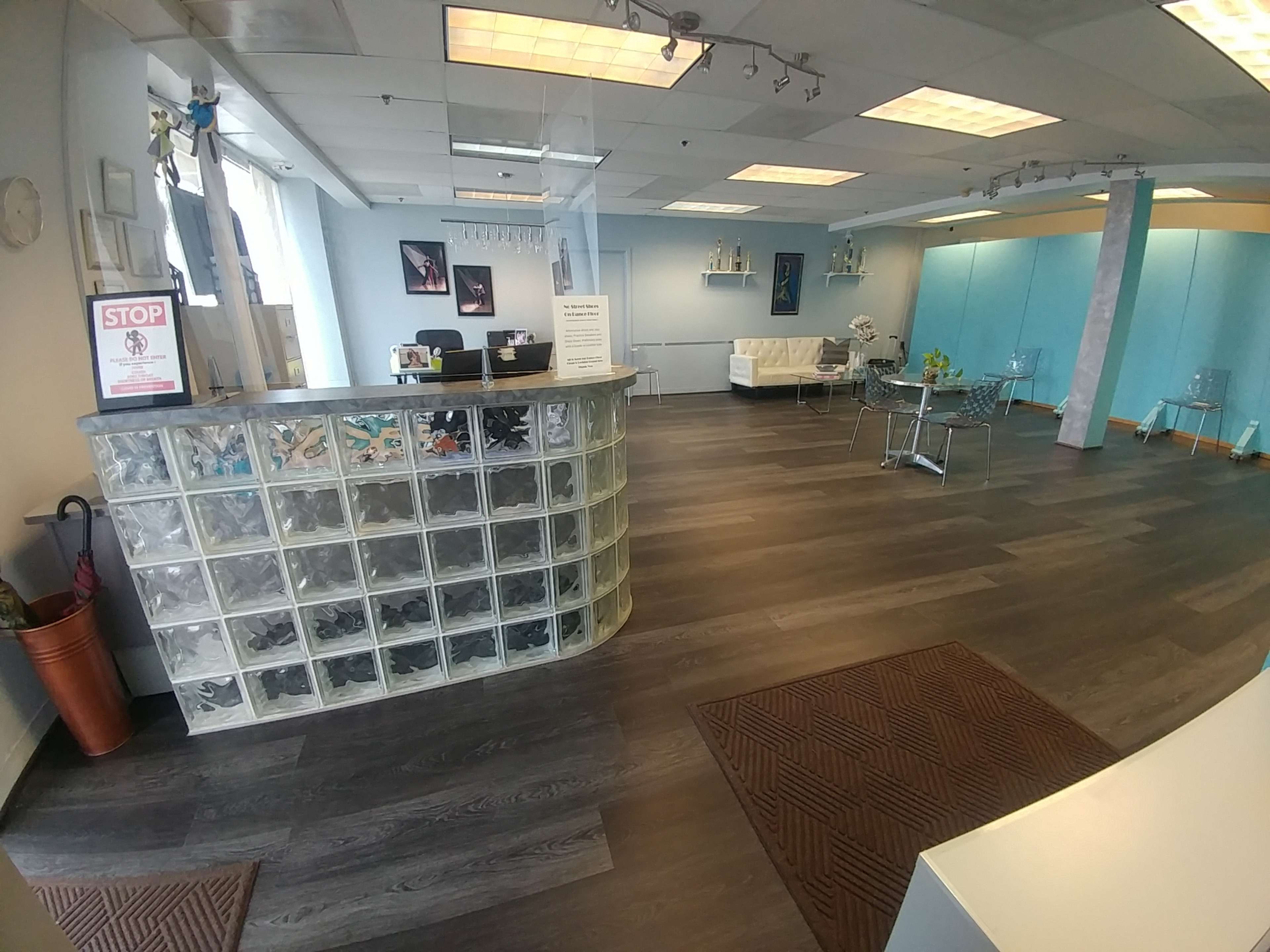 A modern reception area with a glass block front desk, wooden floors, and minimalistic furniture.