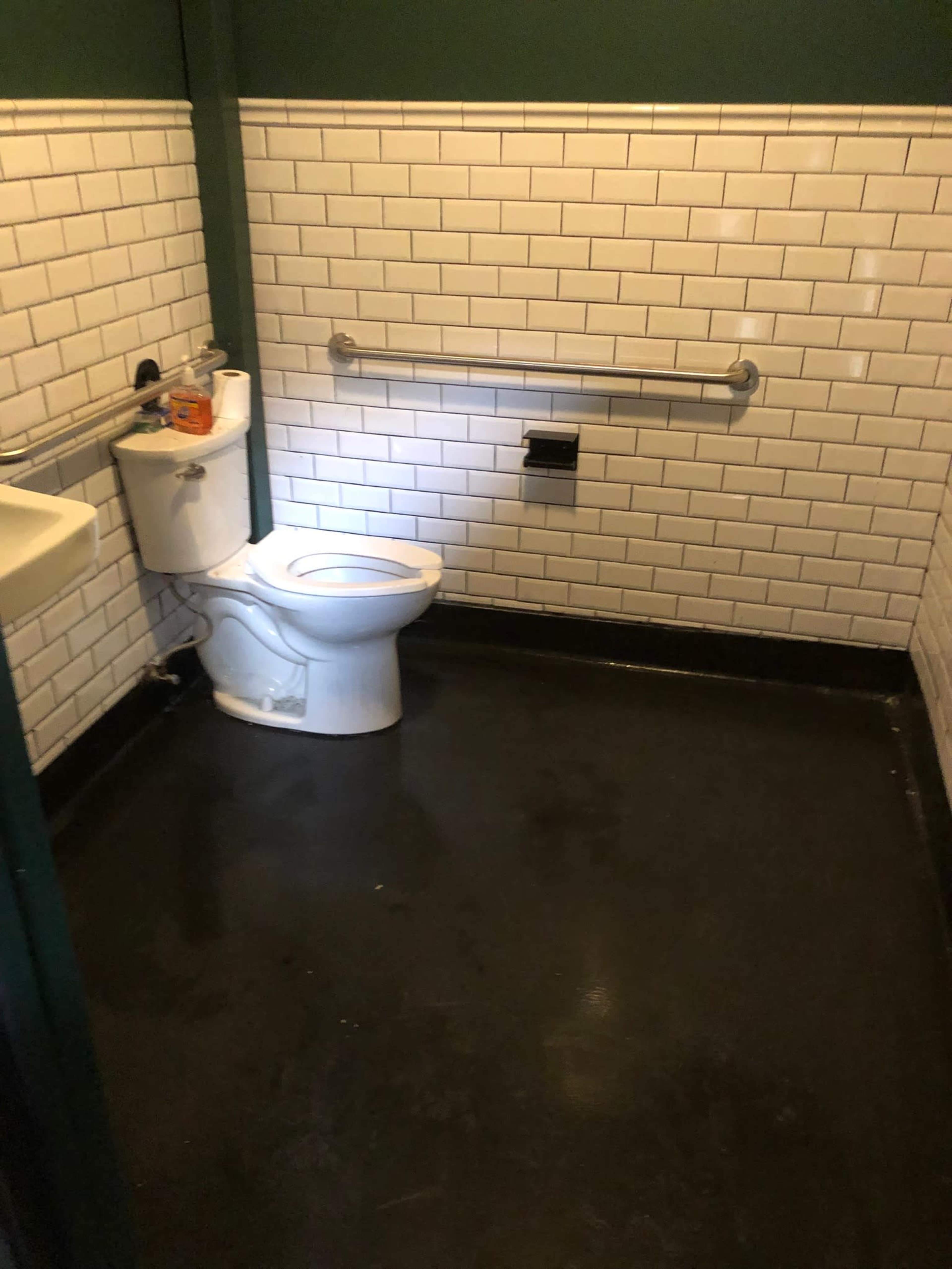 A small restroom with white tiled walls, a toilet, and a sink.