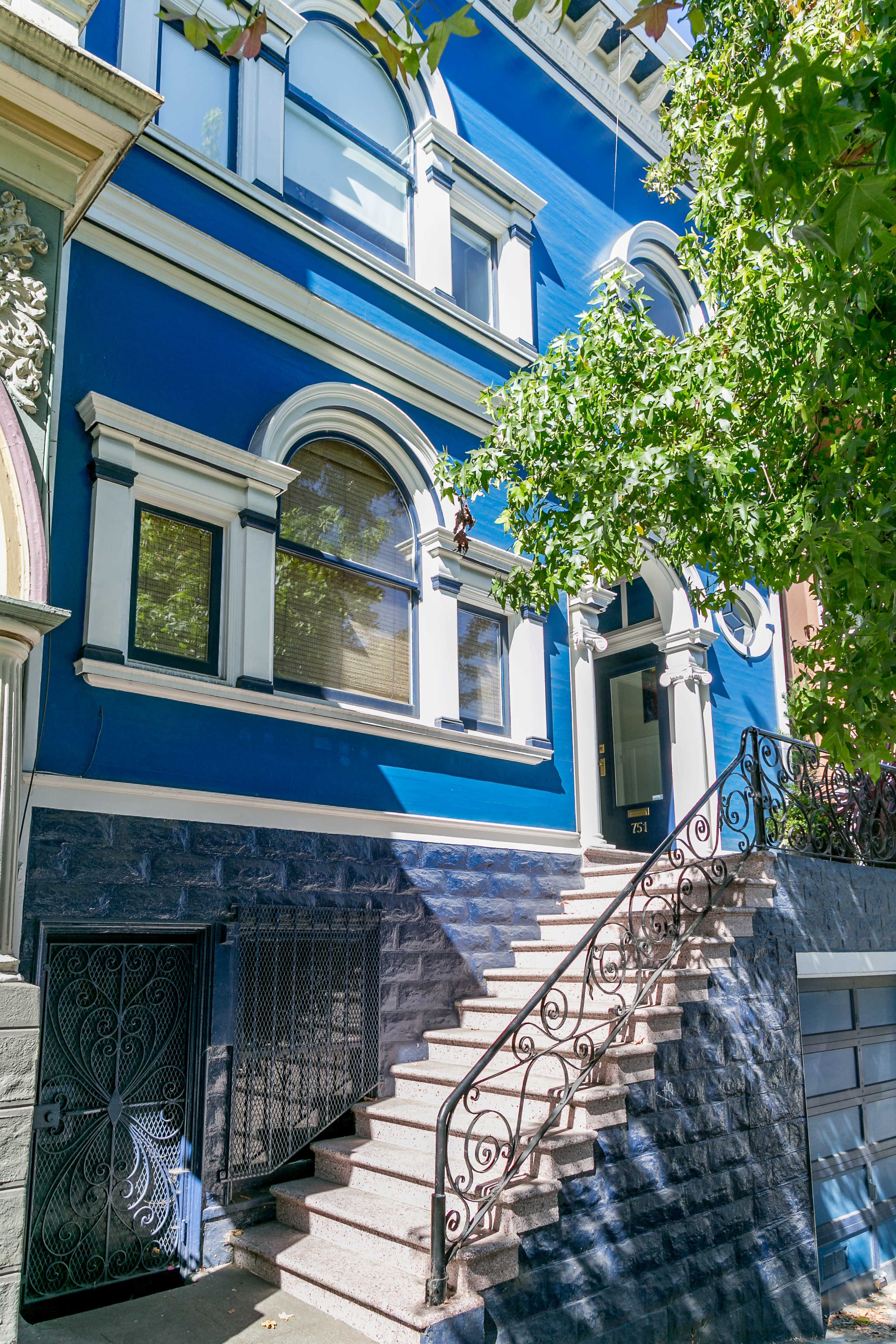 A blue two-story building with decorative trim and a staircase leading up to the entrance.