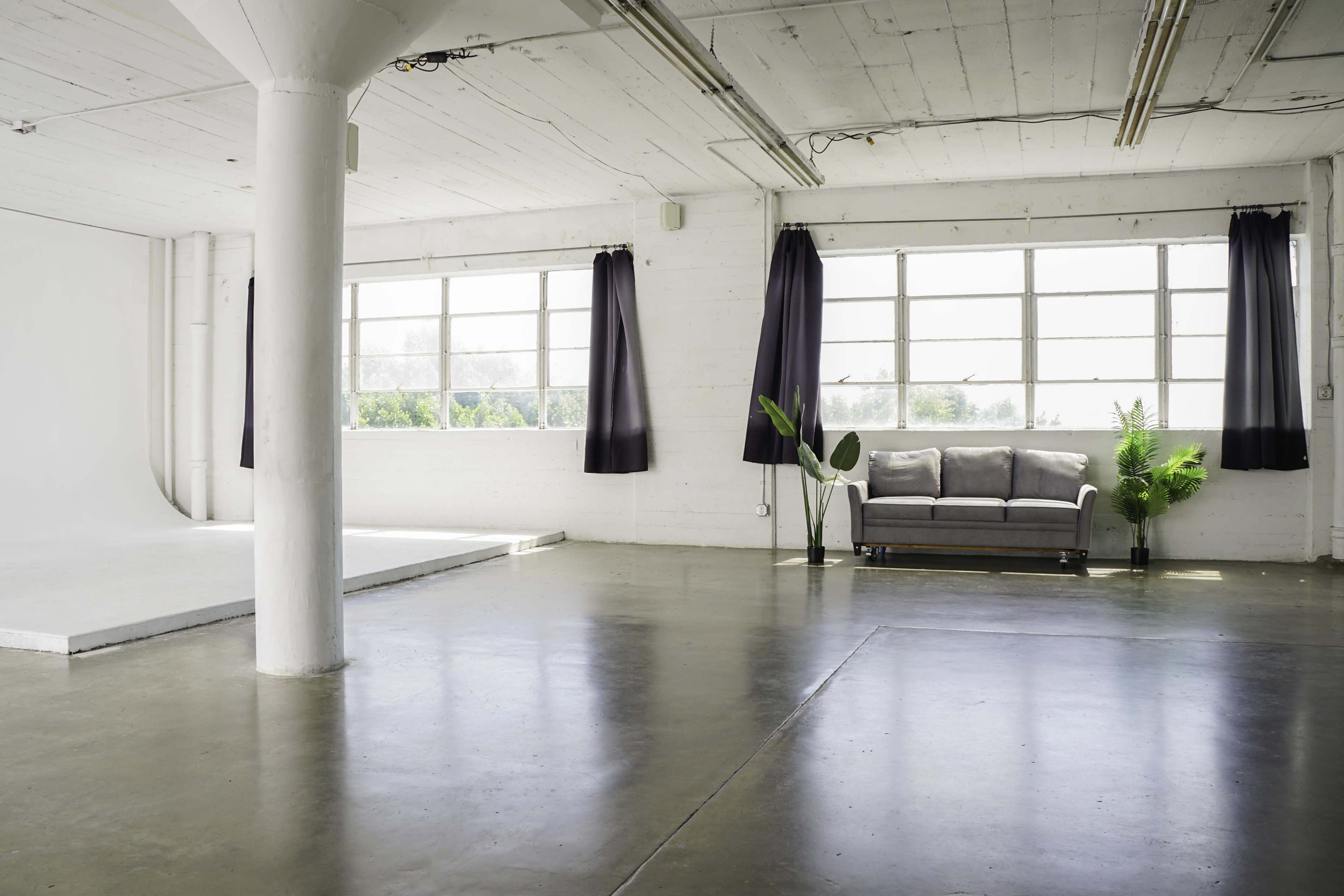 Blackout Loft Studio with central AC, a pre-lit corner cyc wall, Light Tunnel, wooden platform, white wooden reclaimed wall & frameless window with downtown view - PRO II Image in Central LA, Los Angeles, CA
