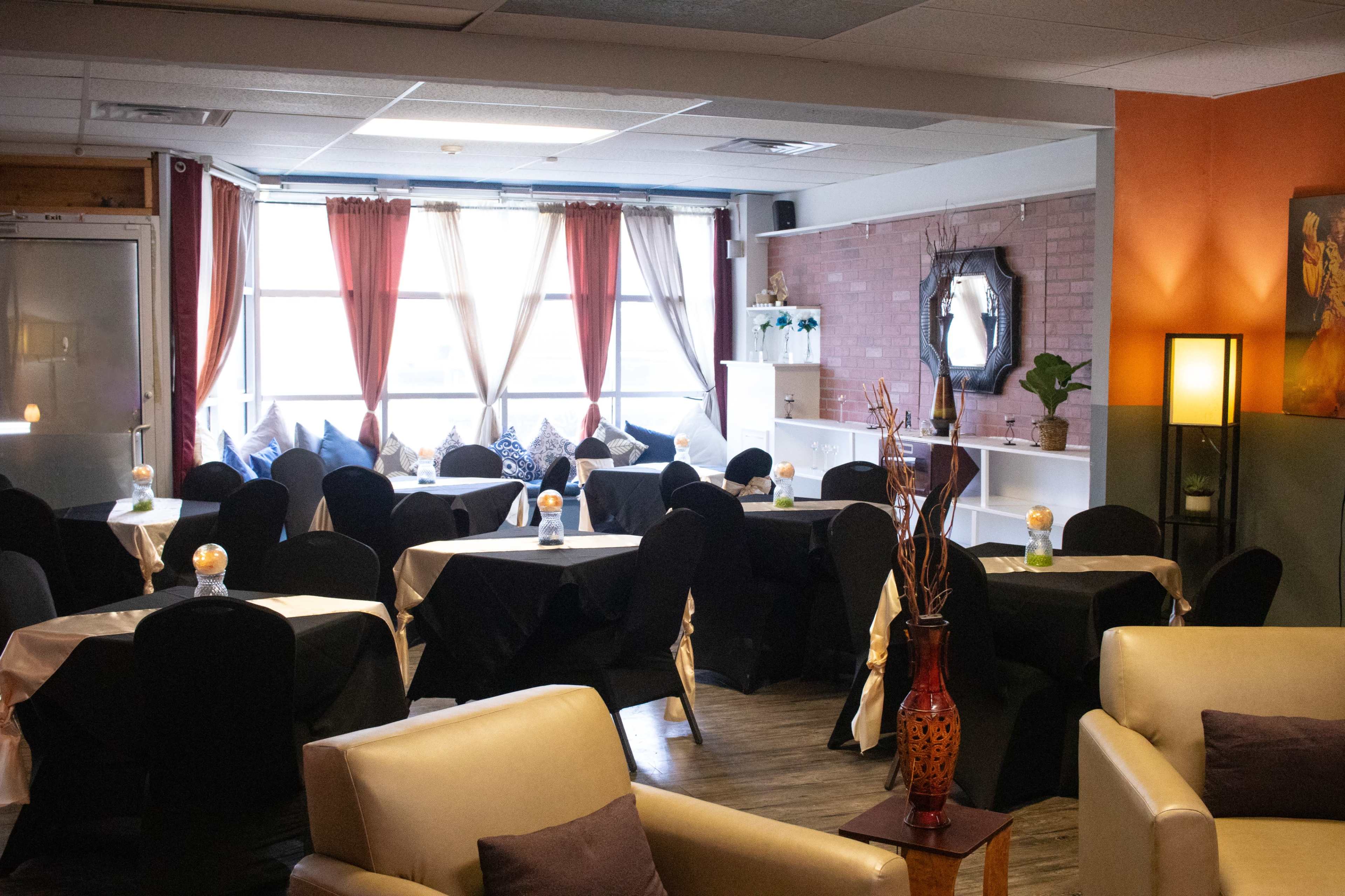 A cozy dining area with black tablecloths and illuminated centerpieces positioned around neatly arranged tables.