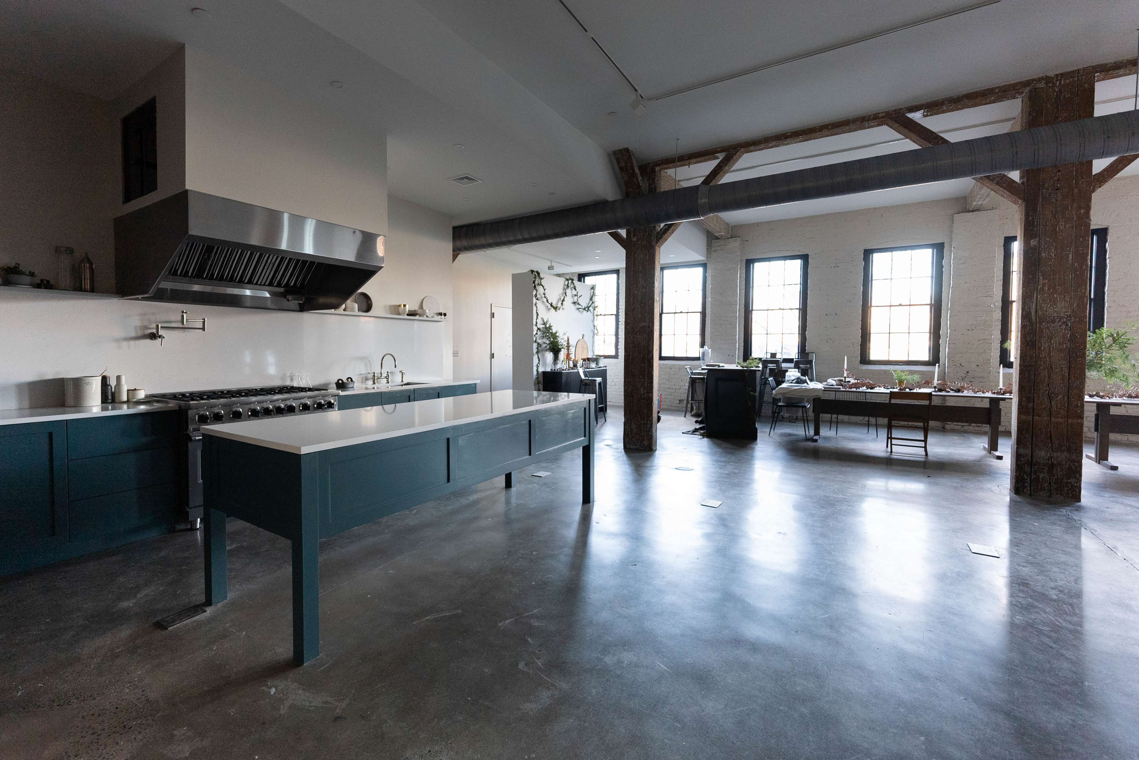 A modern kitchen featuring a large central island, stainless steel appliances, and large windows with natural light illuminating the space.