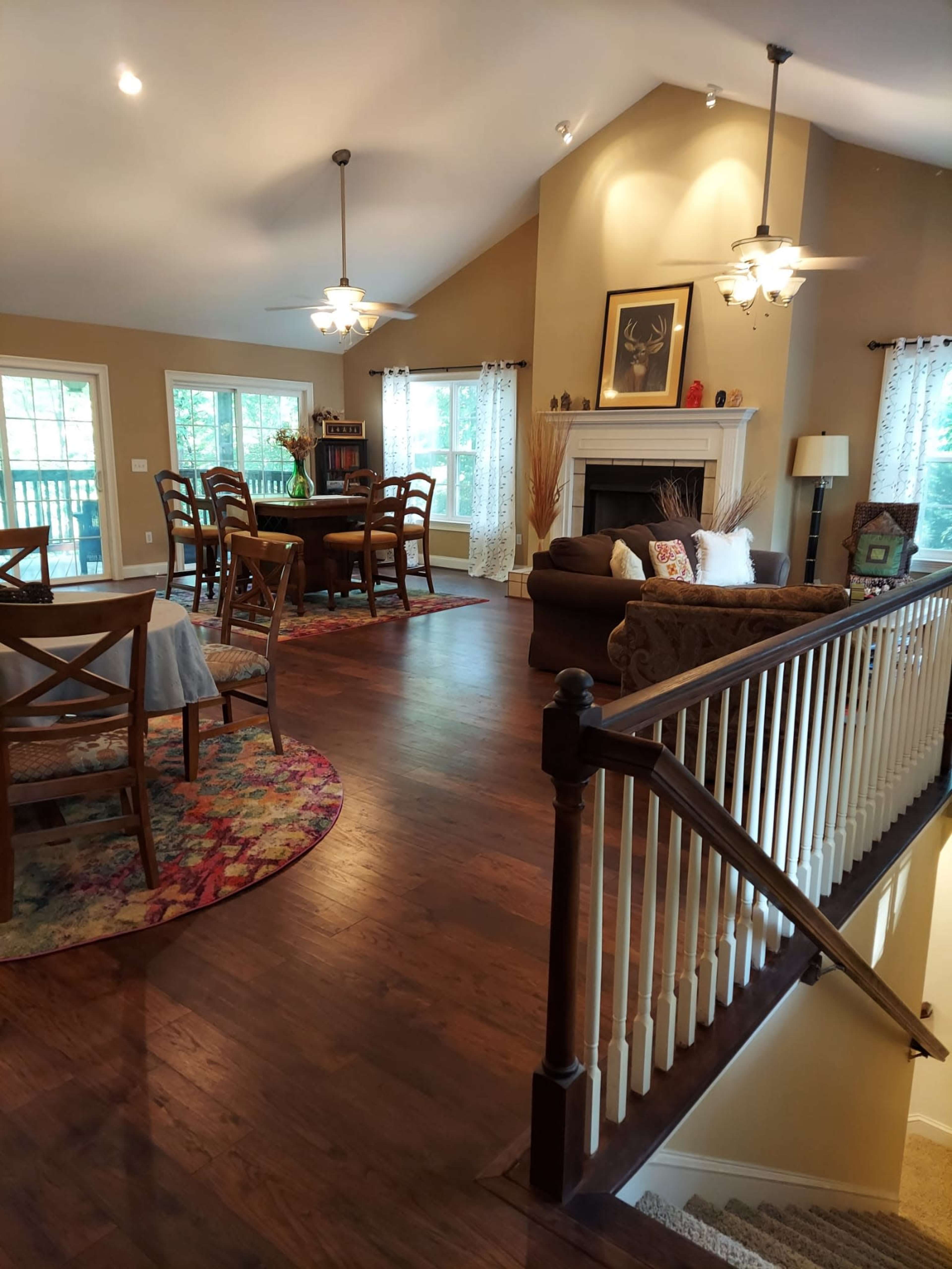 A spacious living area with a dining table, a cozy seating arrangement, a fireplace, and large windows allowing natural light.