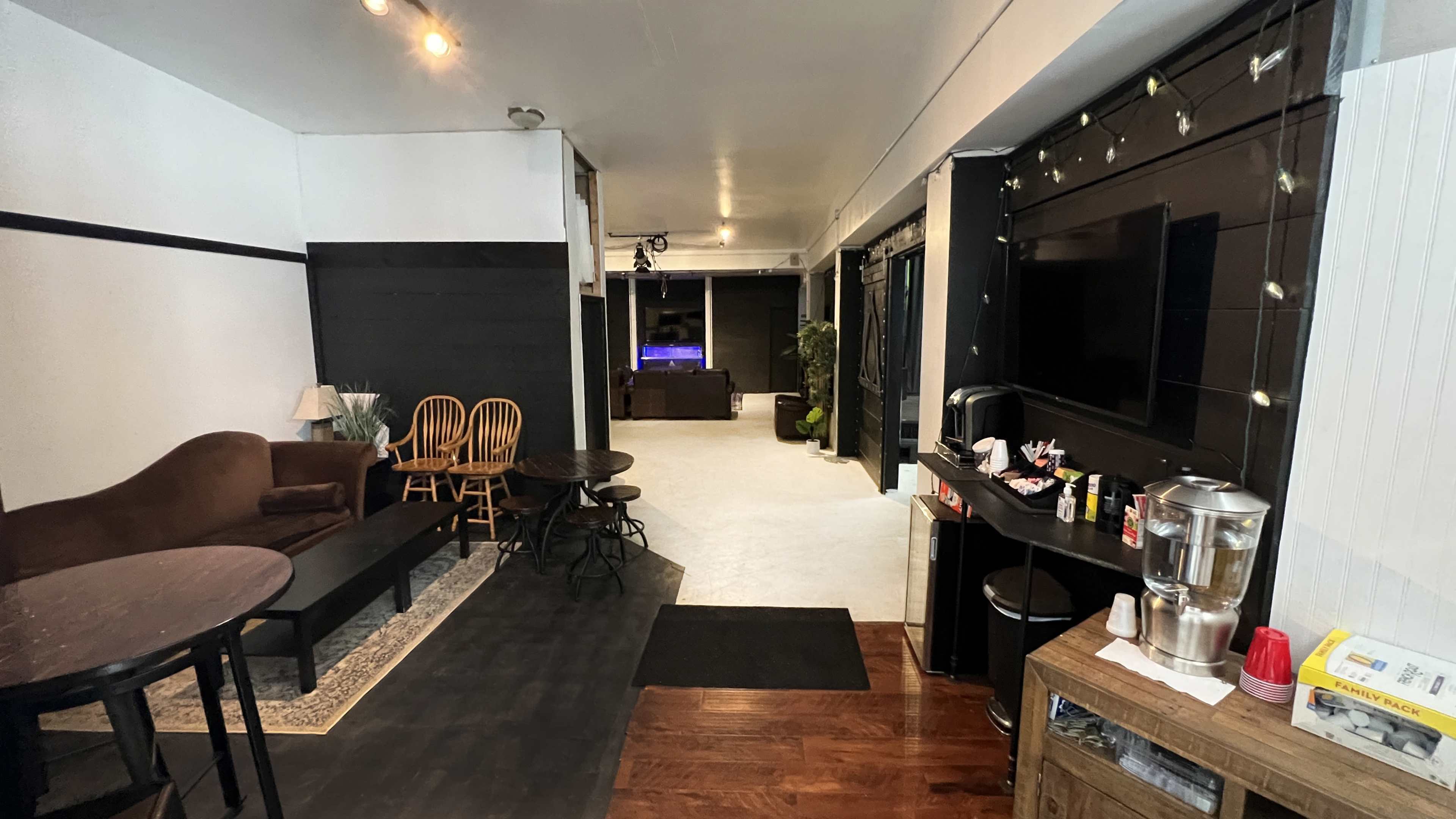 A spacious room divided into a seating area with chairs and tables on the left and an open area with a bar and decorative elements on the right.