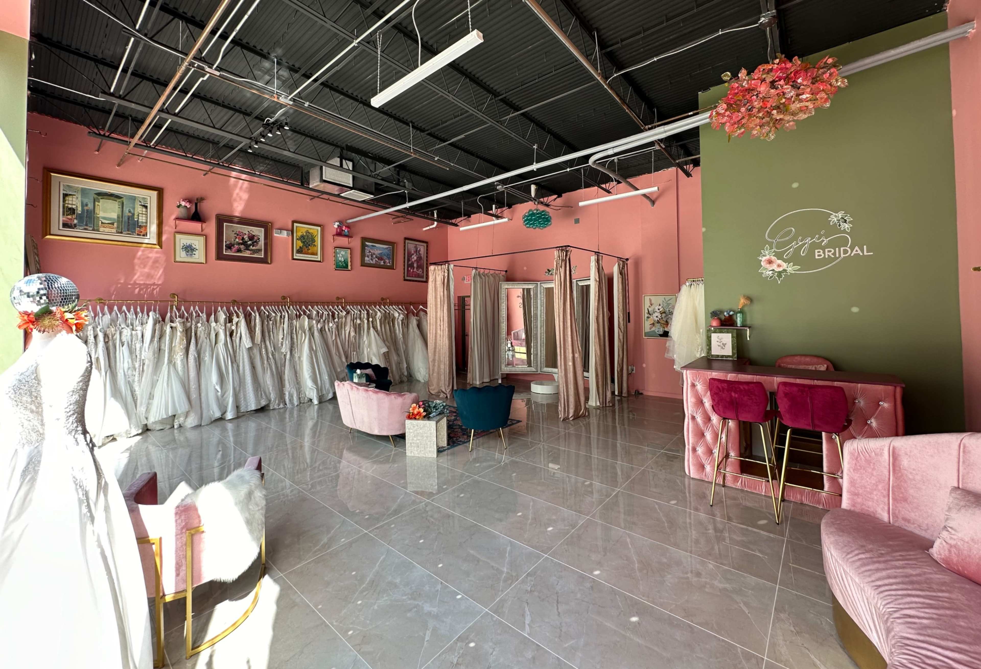 The image shows a bridal shop with rows of wedding dresses hanging on the walls, a seating area, and a reception counter.