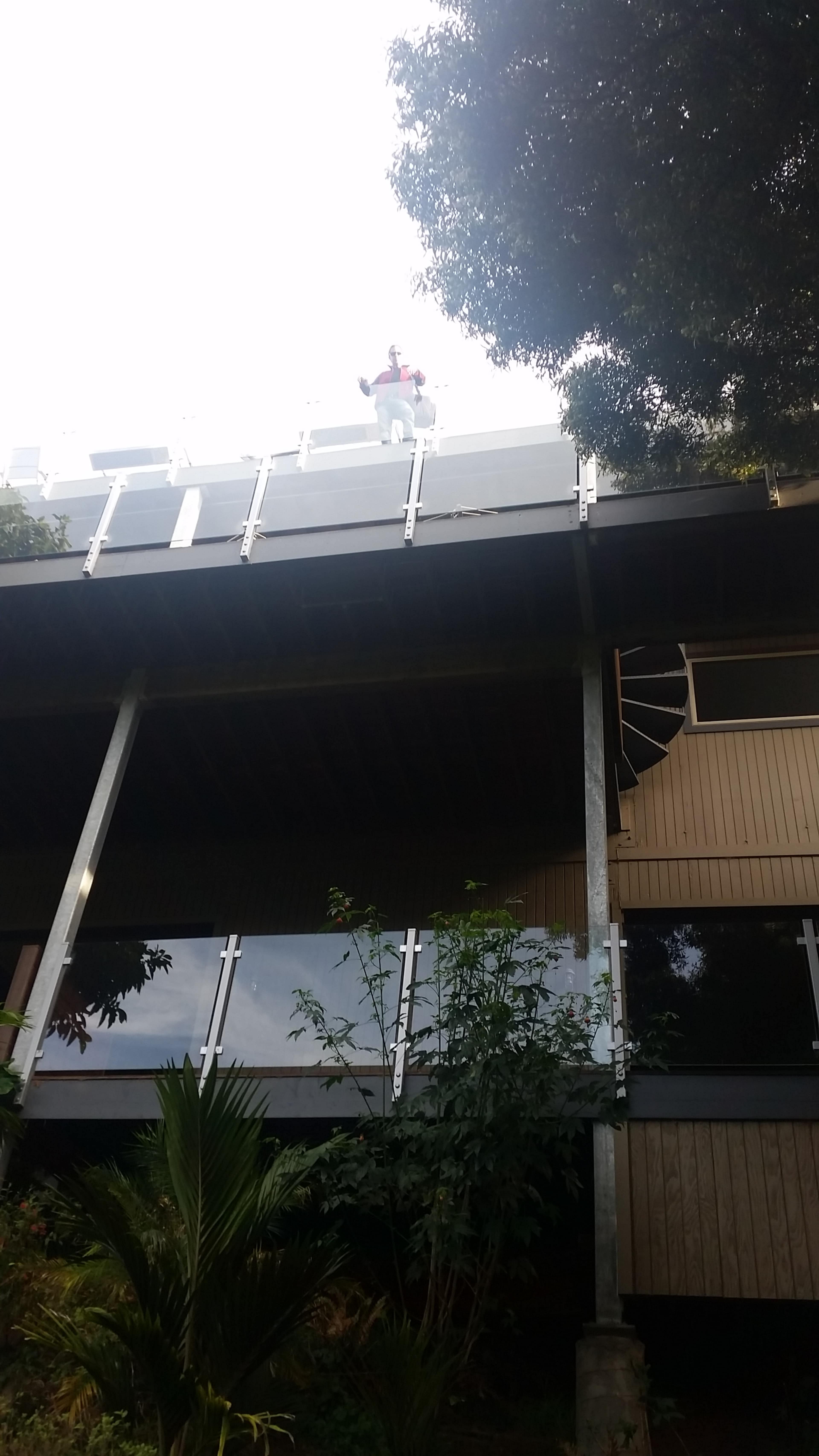 A person dressed in a costume stands on the roof of a building, next to a railing.