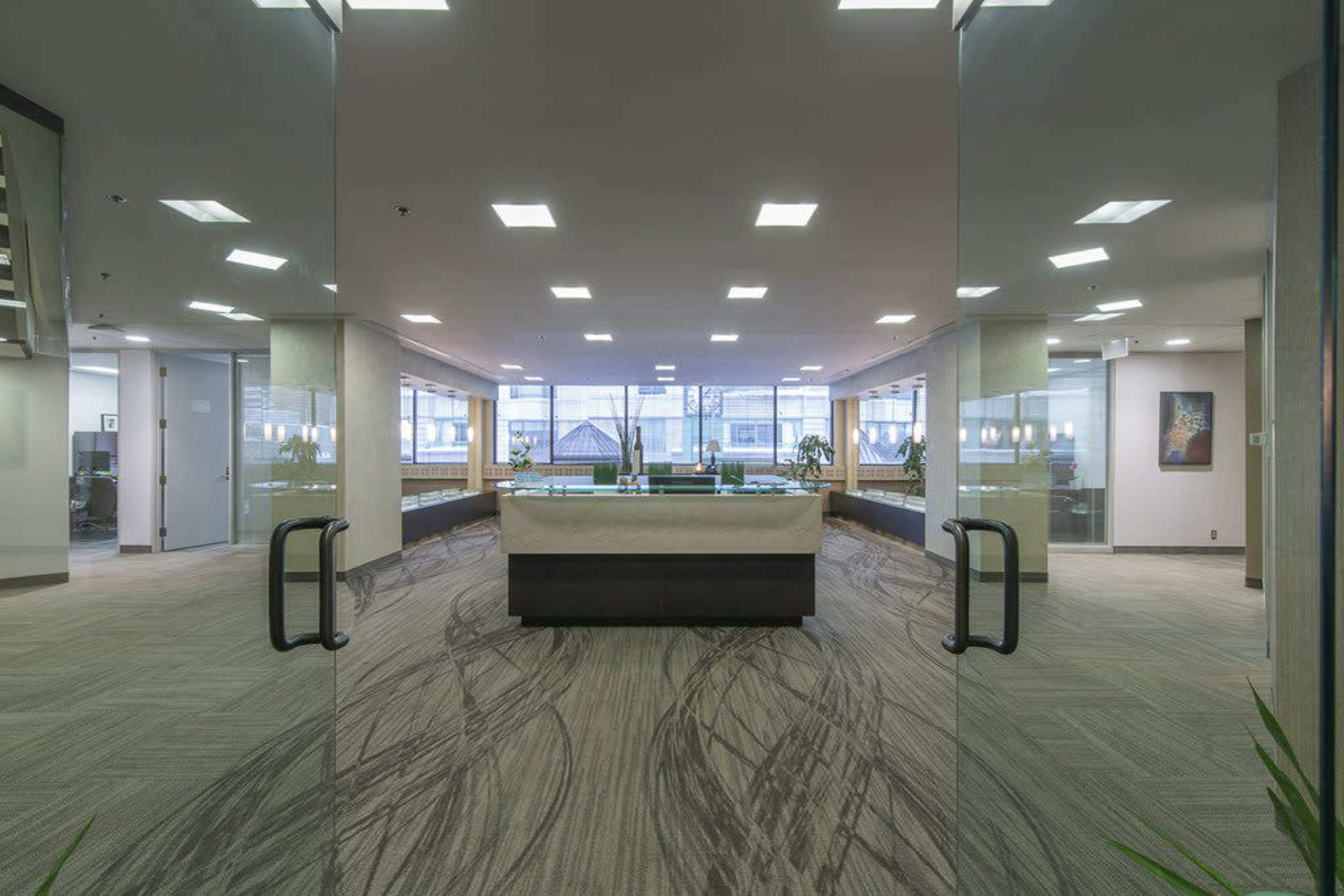A modern office lobby with a central reception desk and large windows allowing natural light to fill the space.
