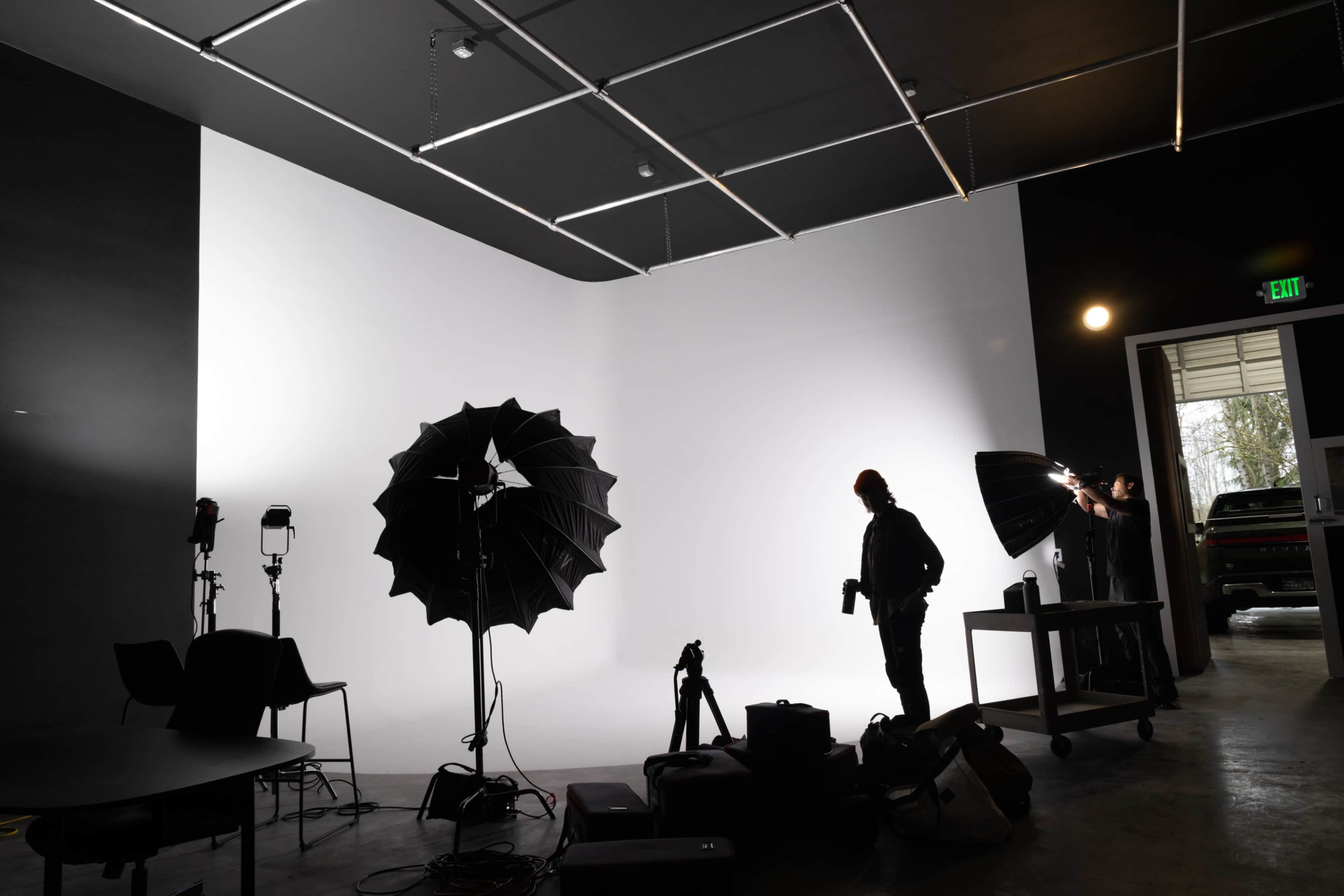 A photographer works in a studio featuring a white backdrop and multiple lighting setups.