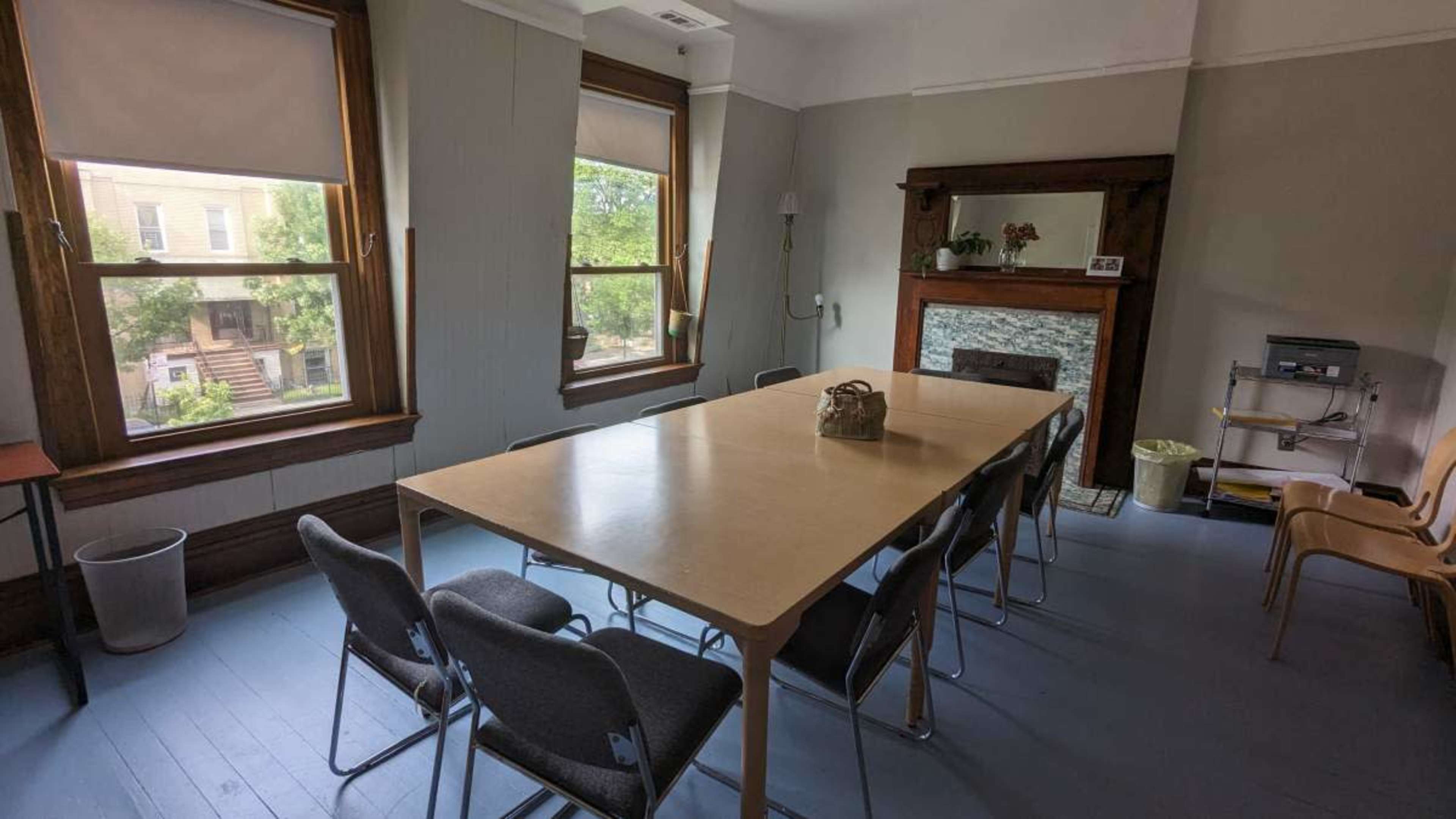 The image shows a conference room with a long wooden table surrounded by several chairs, large windows, and a fireplace on one wall.