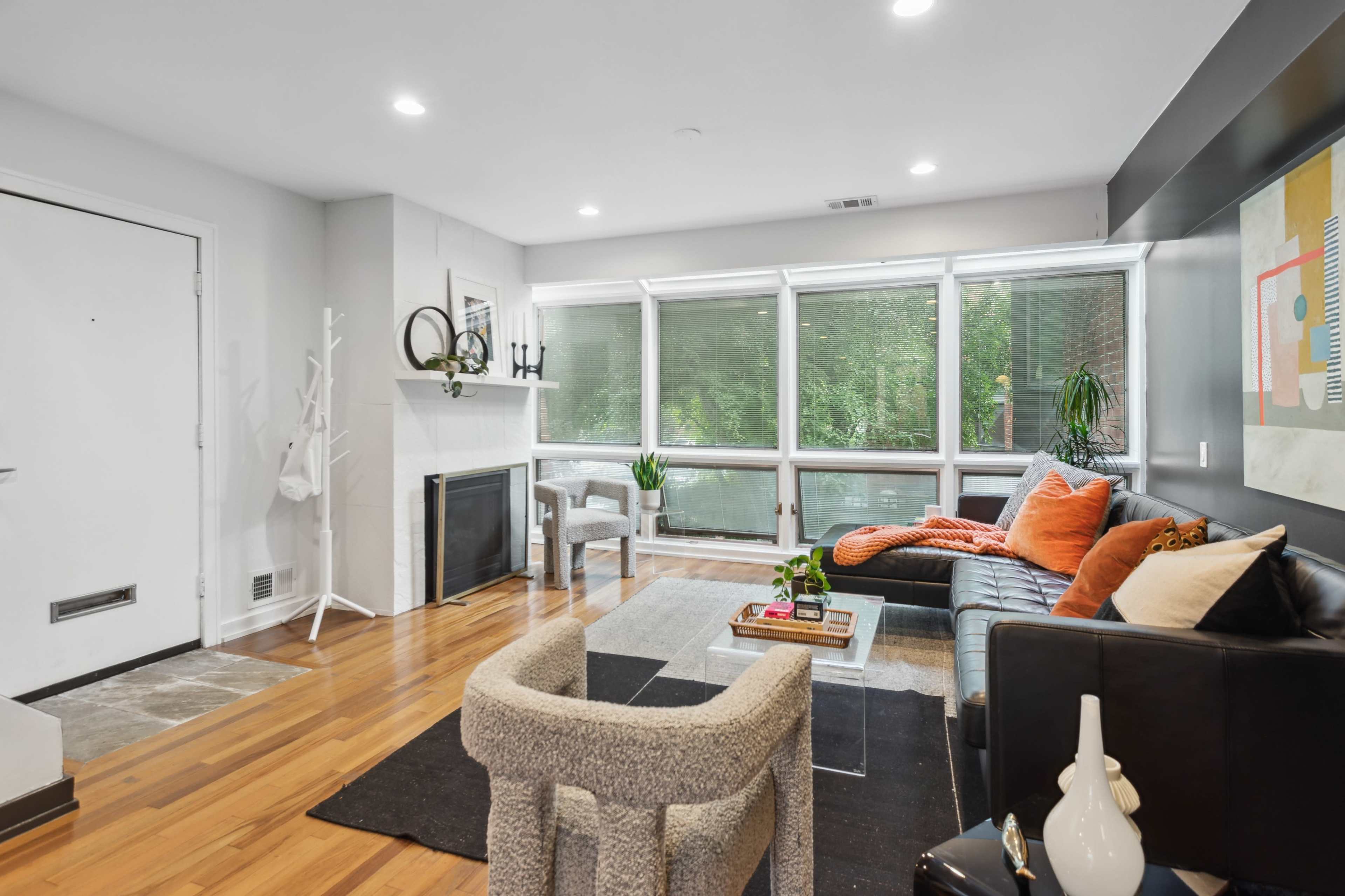 A modern living room featuring large windows, a fireplace, and contemporary furniture in a neutral color palette.