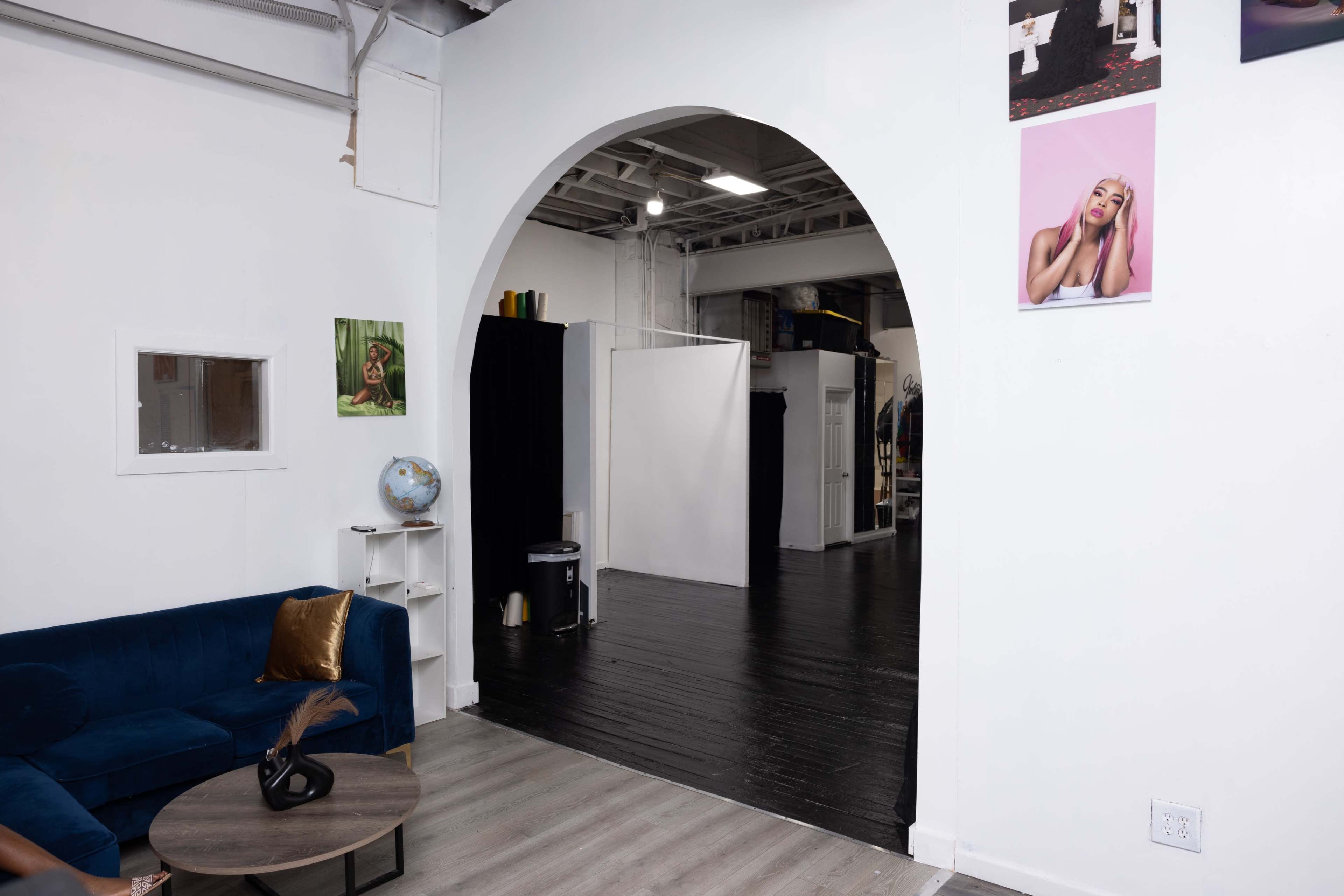 The image shows a modern open space featuring a blue sofa, a globe on a shelf, and a white partition in the background, along with several framed photos on the walls.