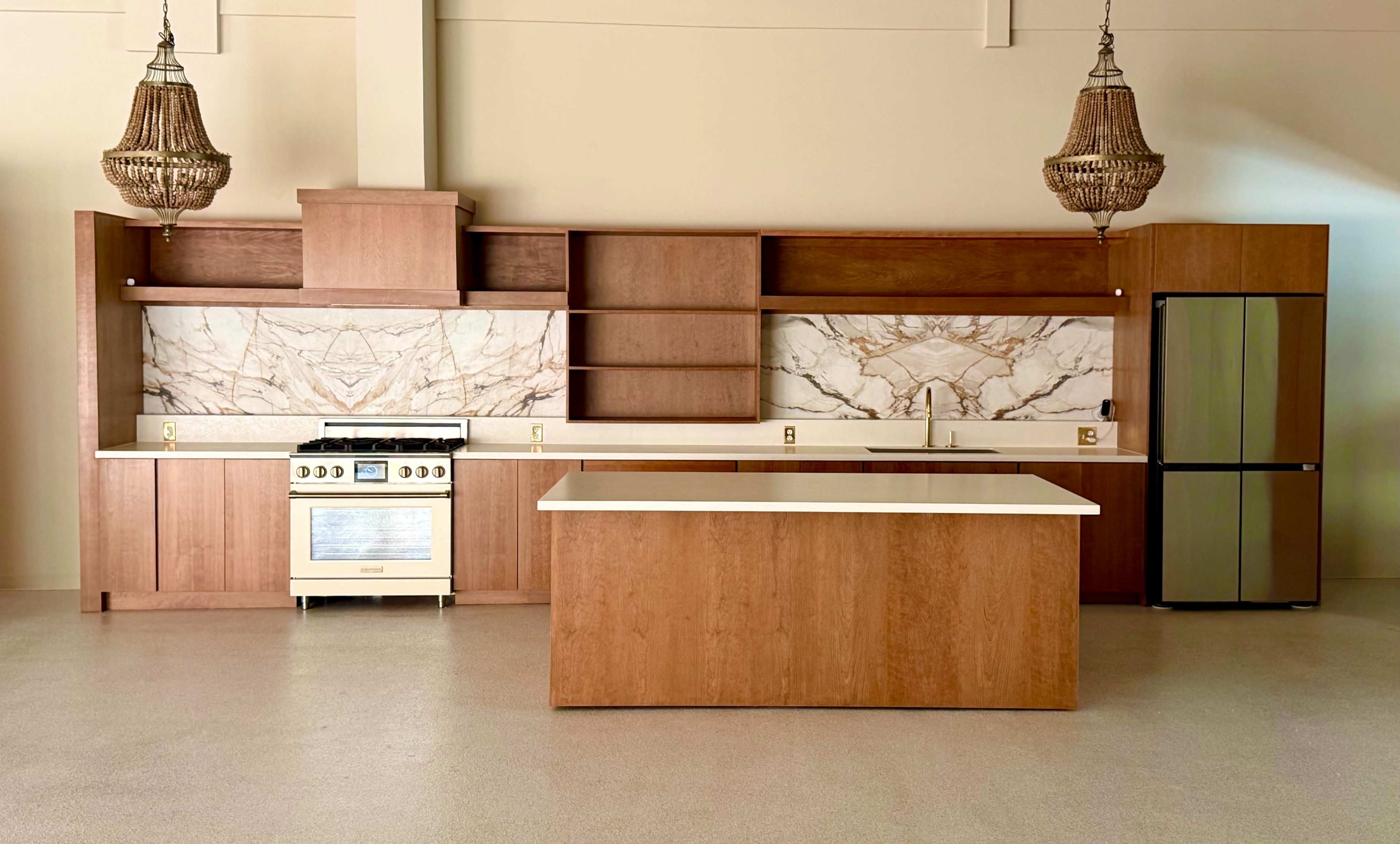 The image shows a modern kitchen with wooden cabinetry, a marble backsplash, and a central island.