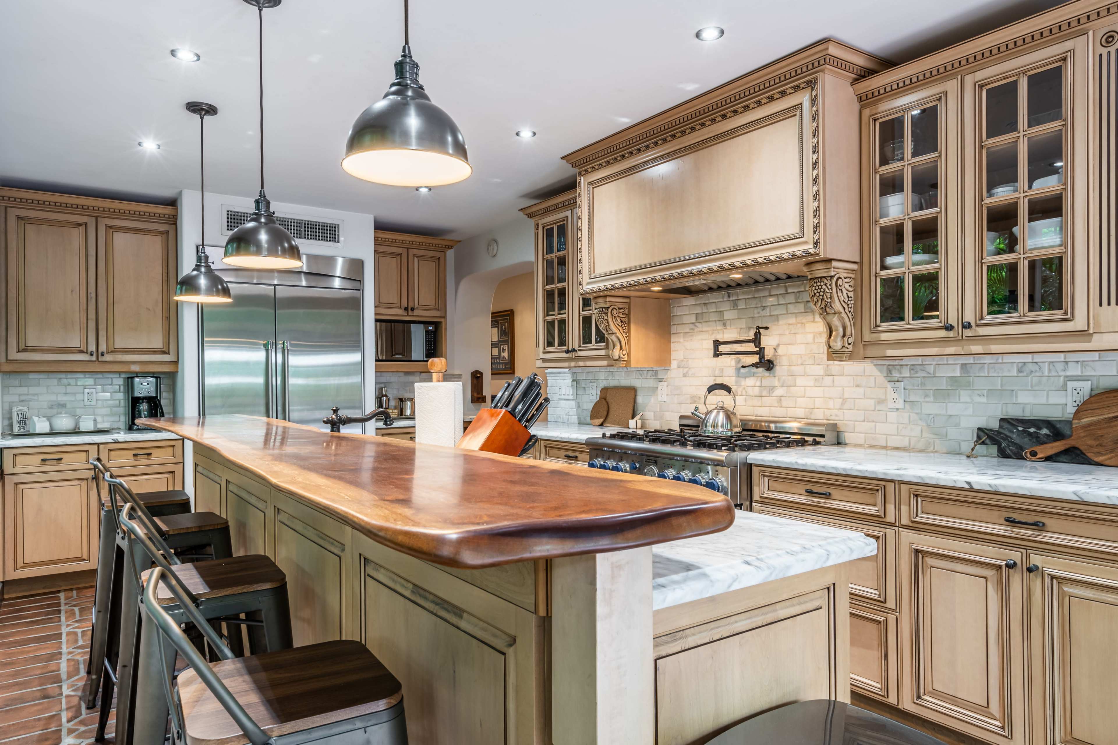 A spacious kitchen with wooden cabinets, a large marble countertop, and stainless steel appliances.