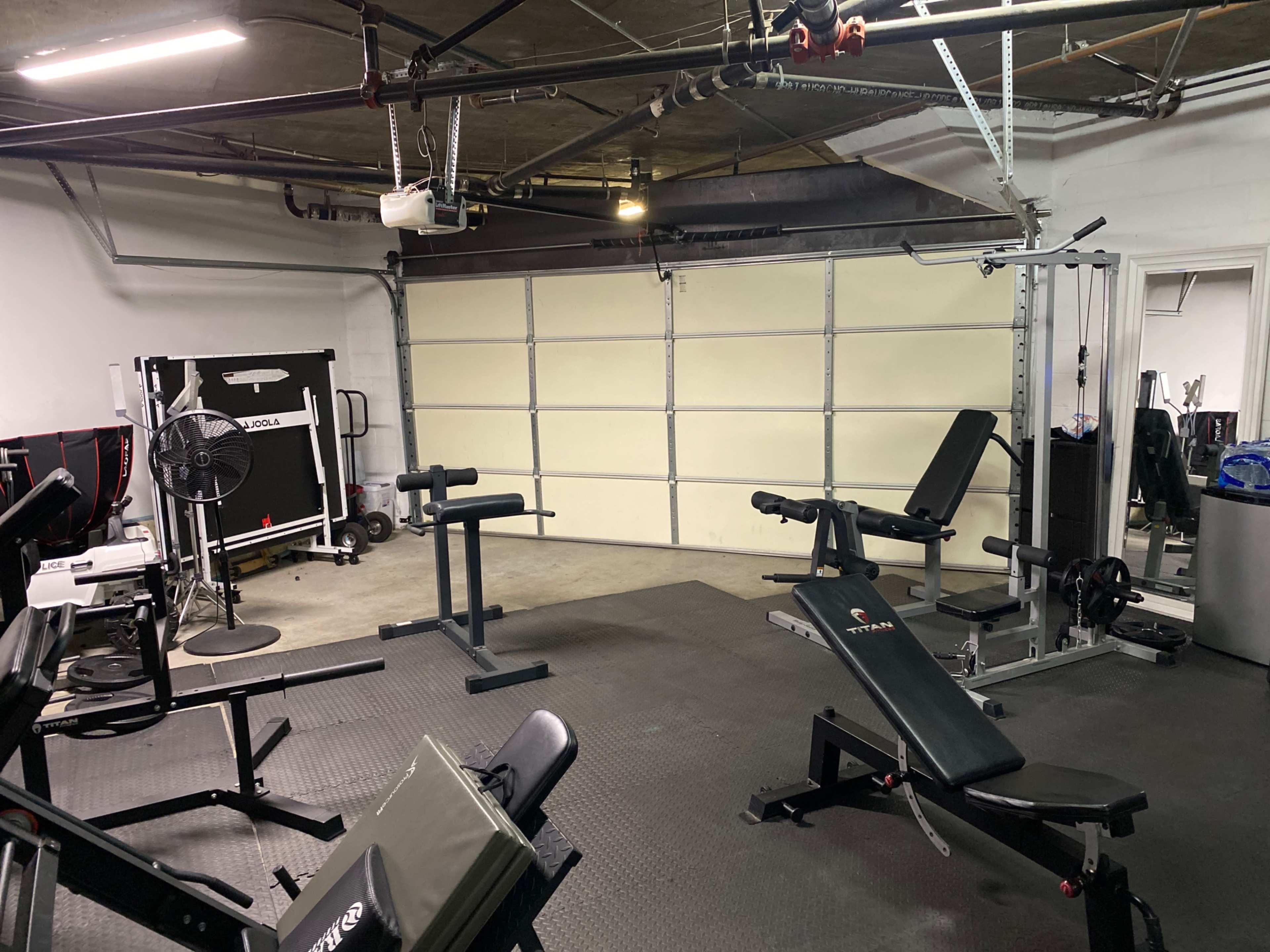 A home gym equipped with various workout machines and weights in a garage space.