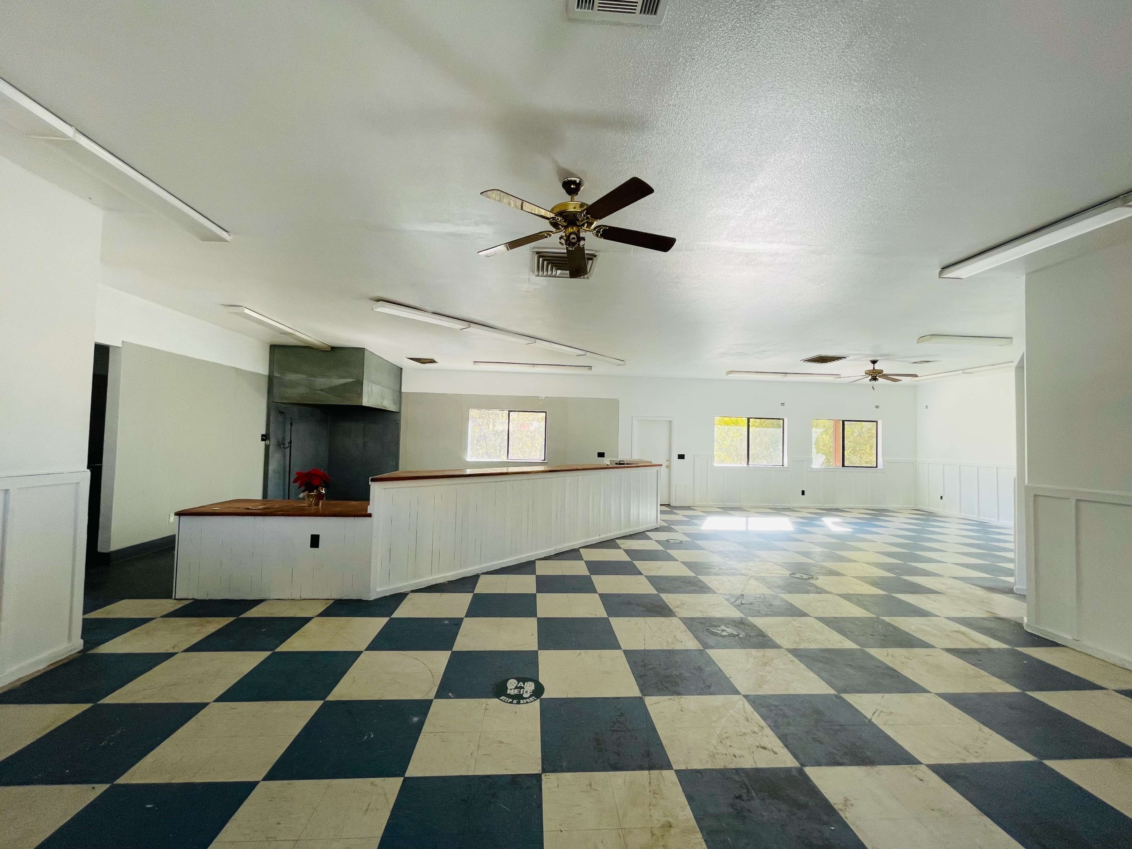 The interior of a vacant room features a checkered blue and white floor and a long counter with a wooden surface.