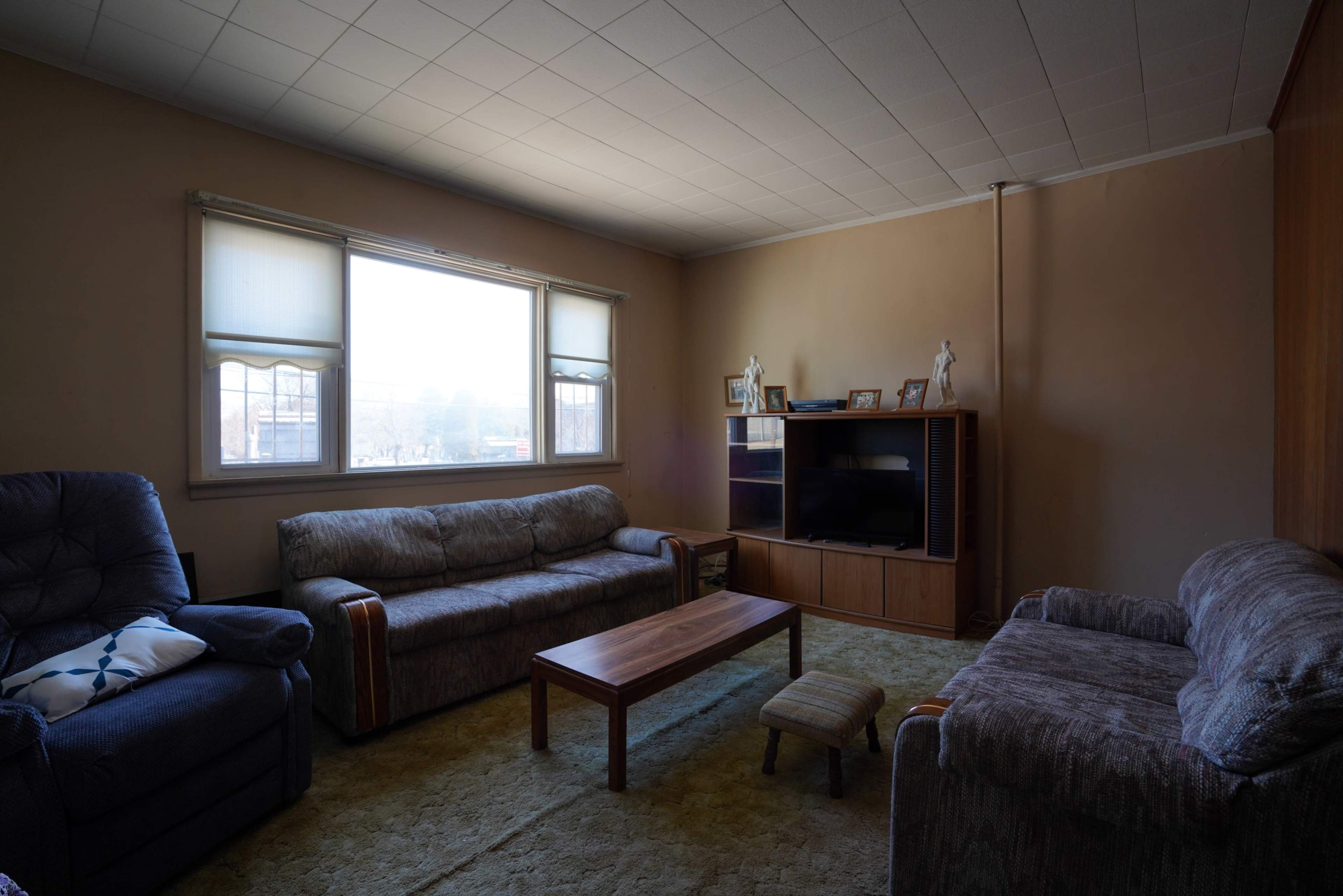 A sparsely furnished living room with two sofas, a coffee table, and a television unit against a wall.