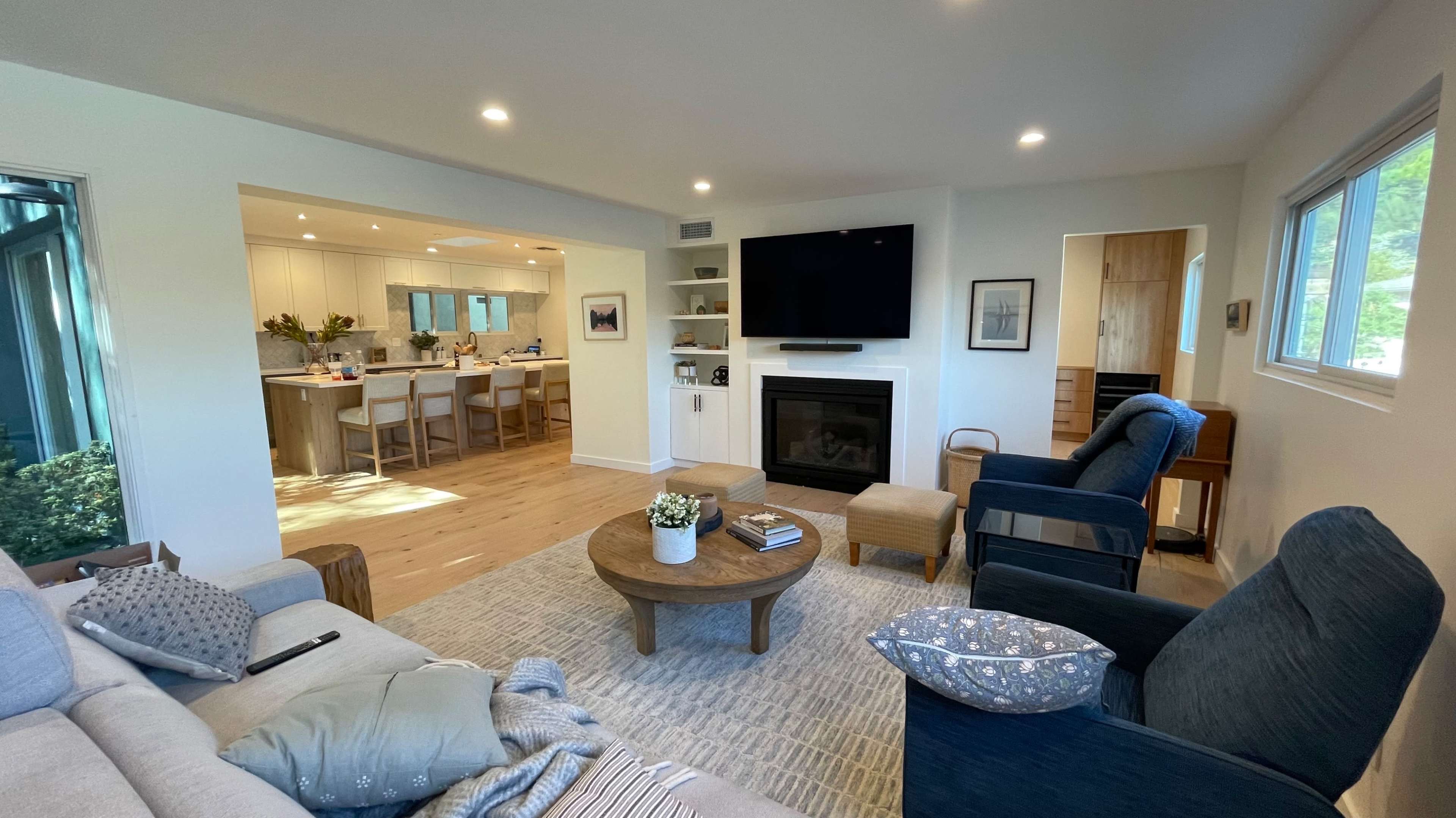 A modern living room with a fireplace, a coffee table, and a view into a bright kitchen area.