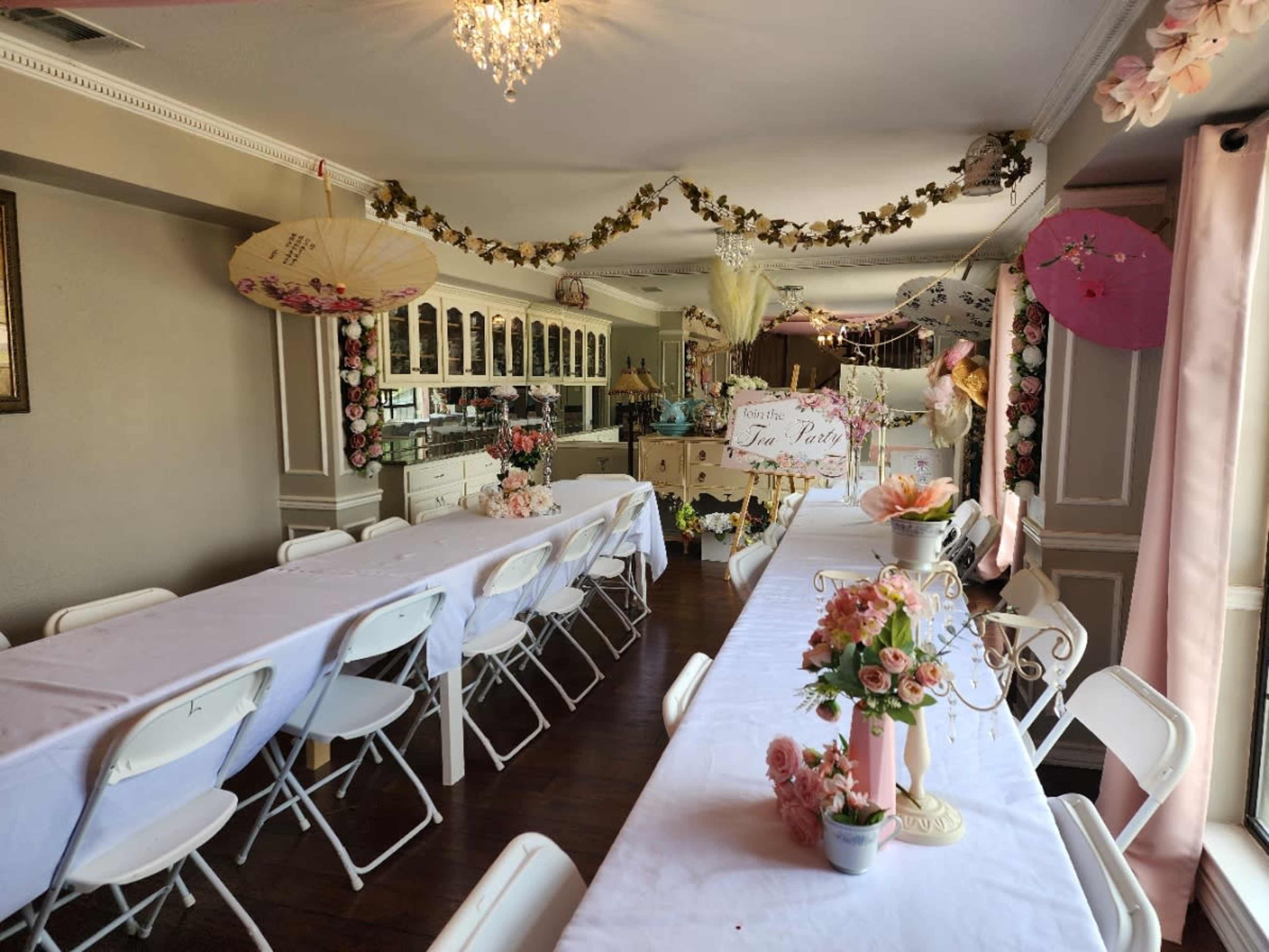 A decorated event space with long tables, floral arrangements, and paper umbrellas hanging from the ceiling.
