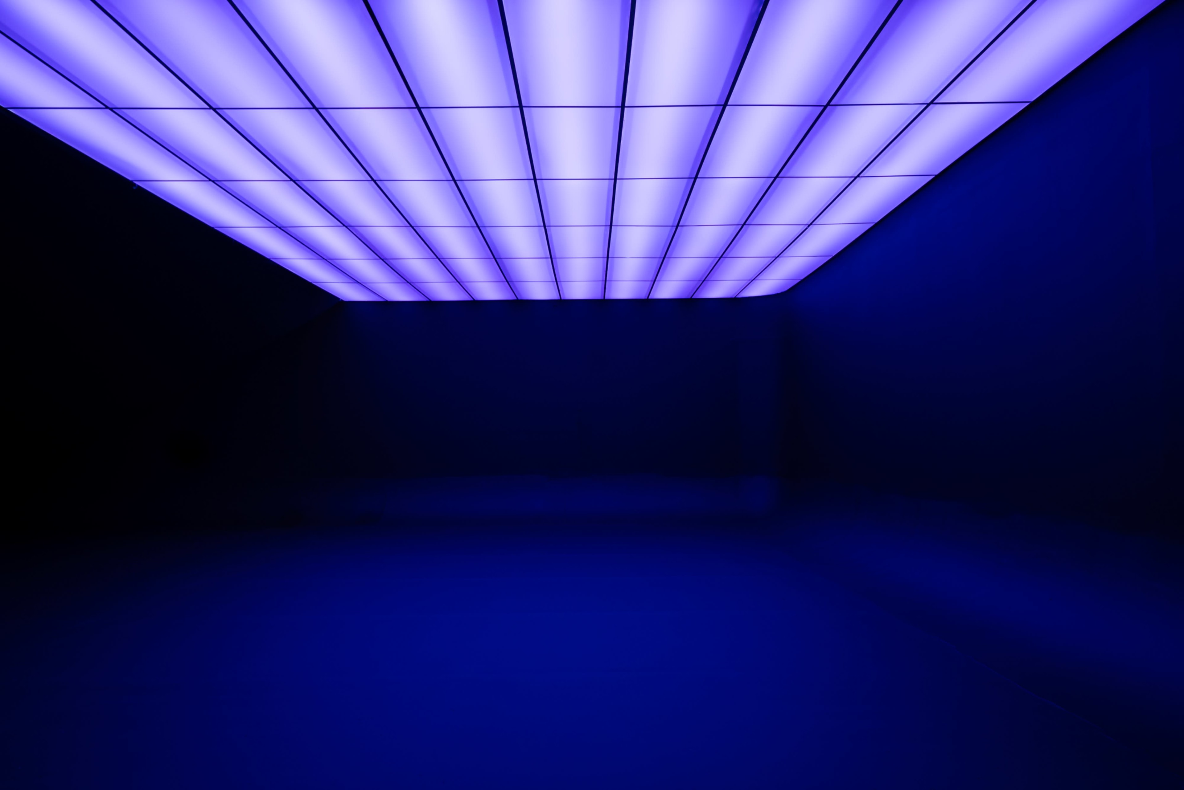 The image shows a dark room illuminated by a grid of purple lights on the ceiling.