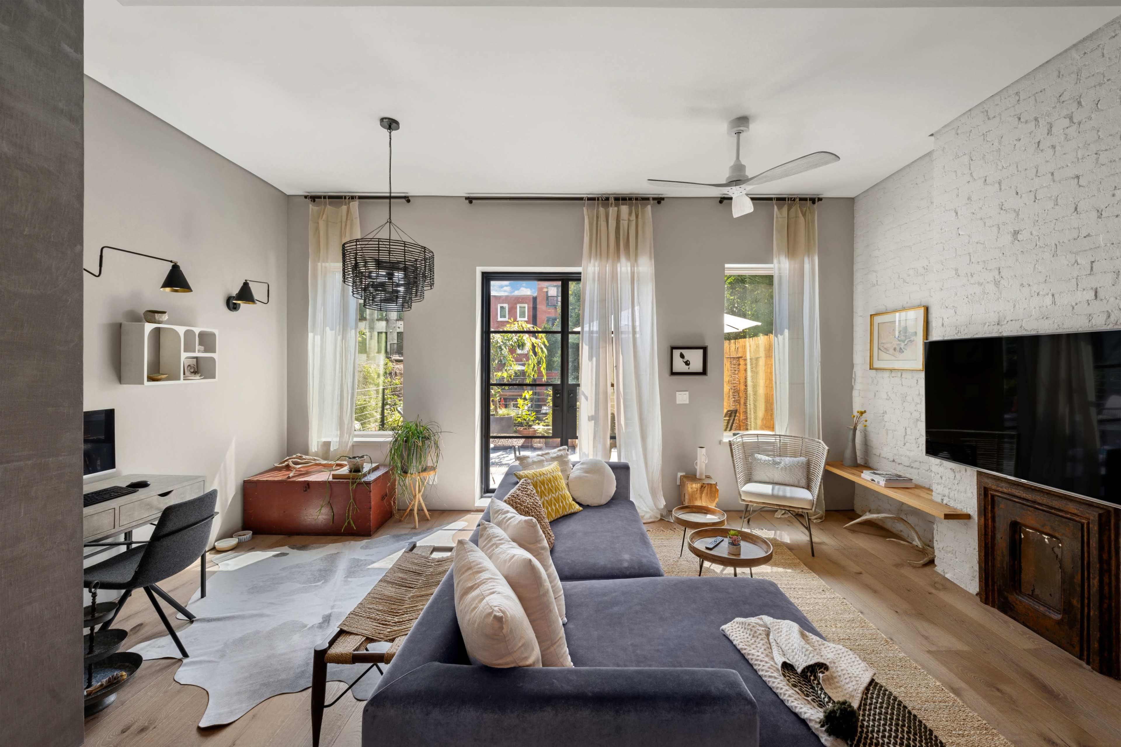 A modern living room featuring a gray sofa, a wooden coffee table, and large windows that allow natural light to illuminate the space.