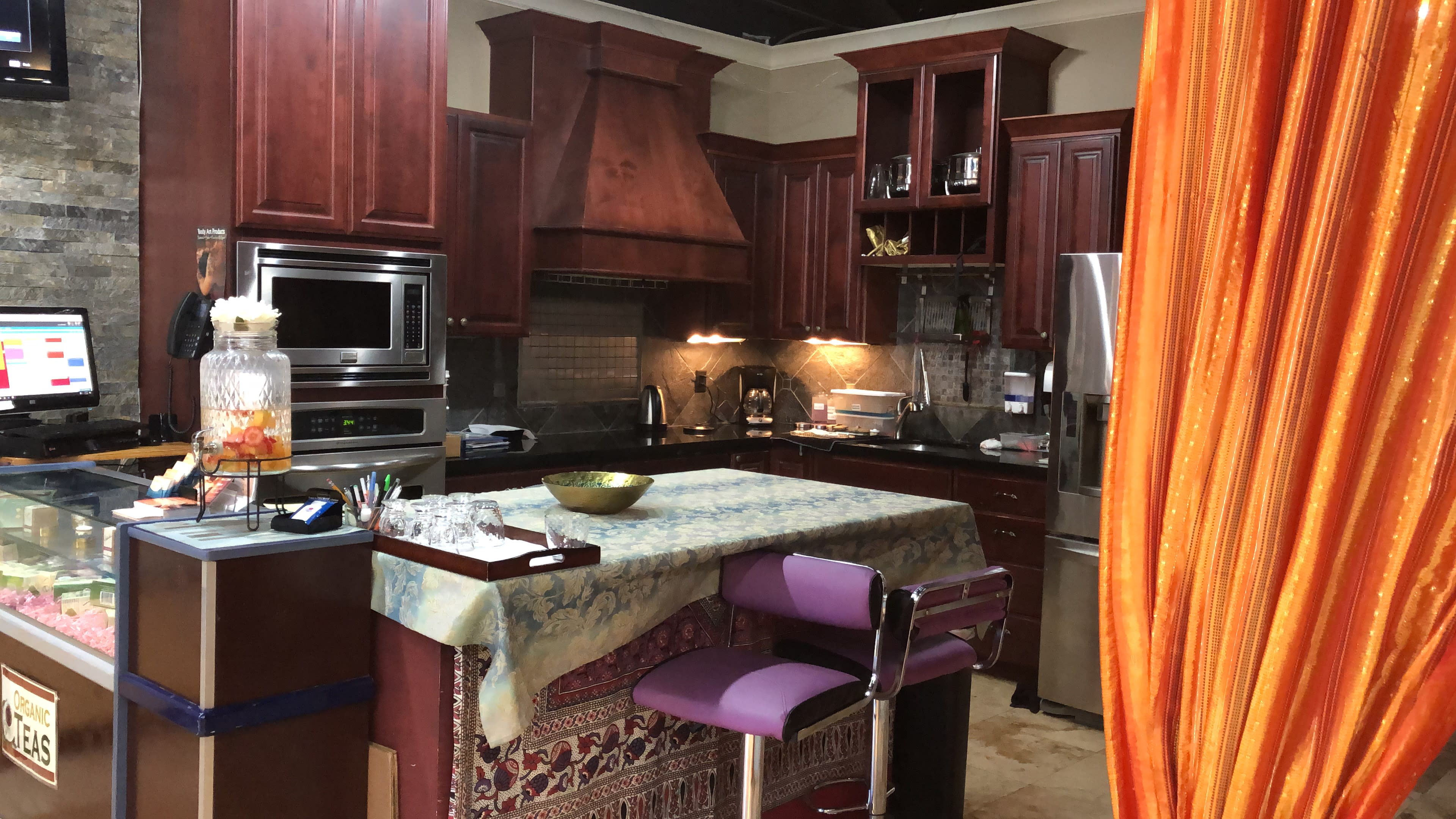 A modern kitchen with dark wooden cabinets, a central island covered by a tablecloth, and a variety of kitchen appliances.