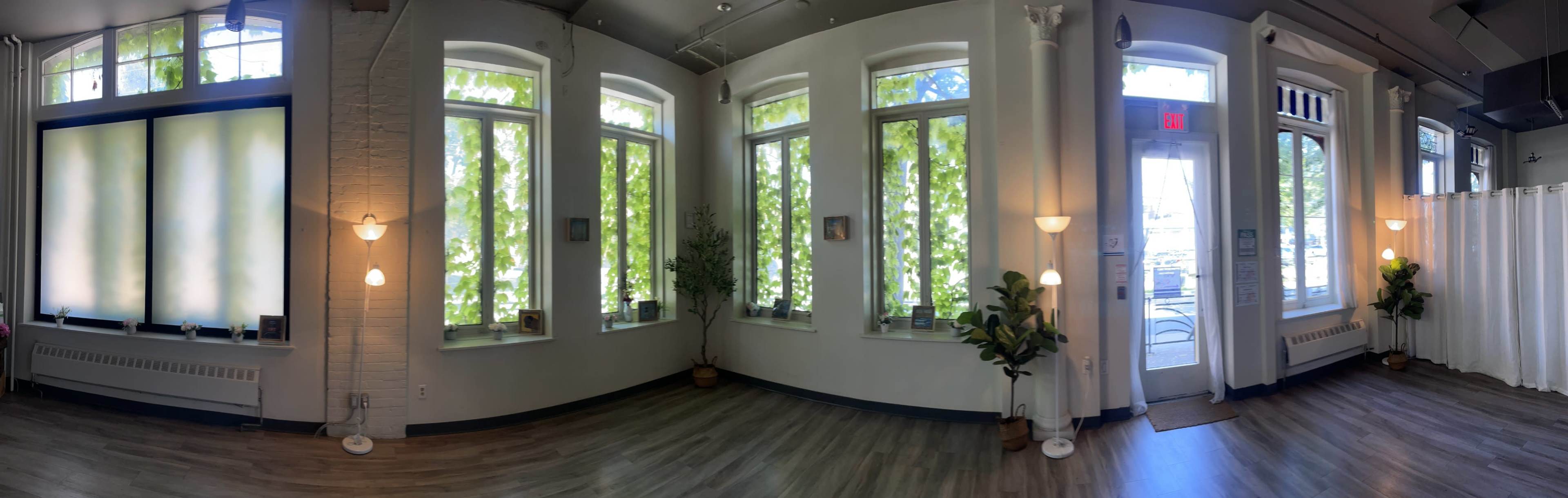 A bright, spacious room with large windows, potted plants, and a door leading outside.