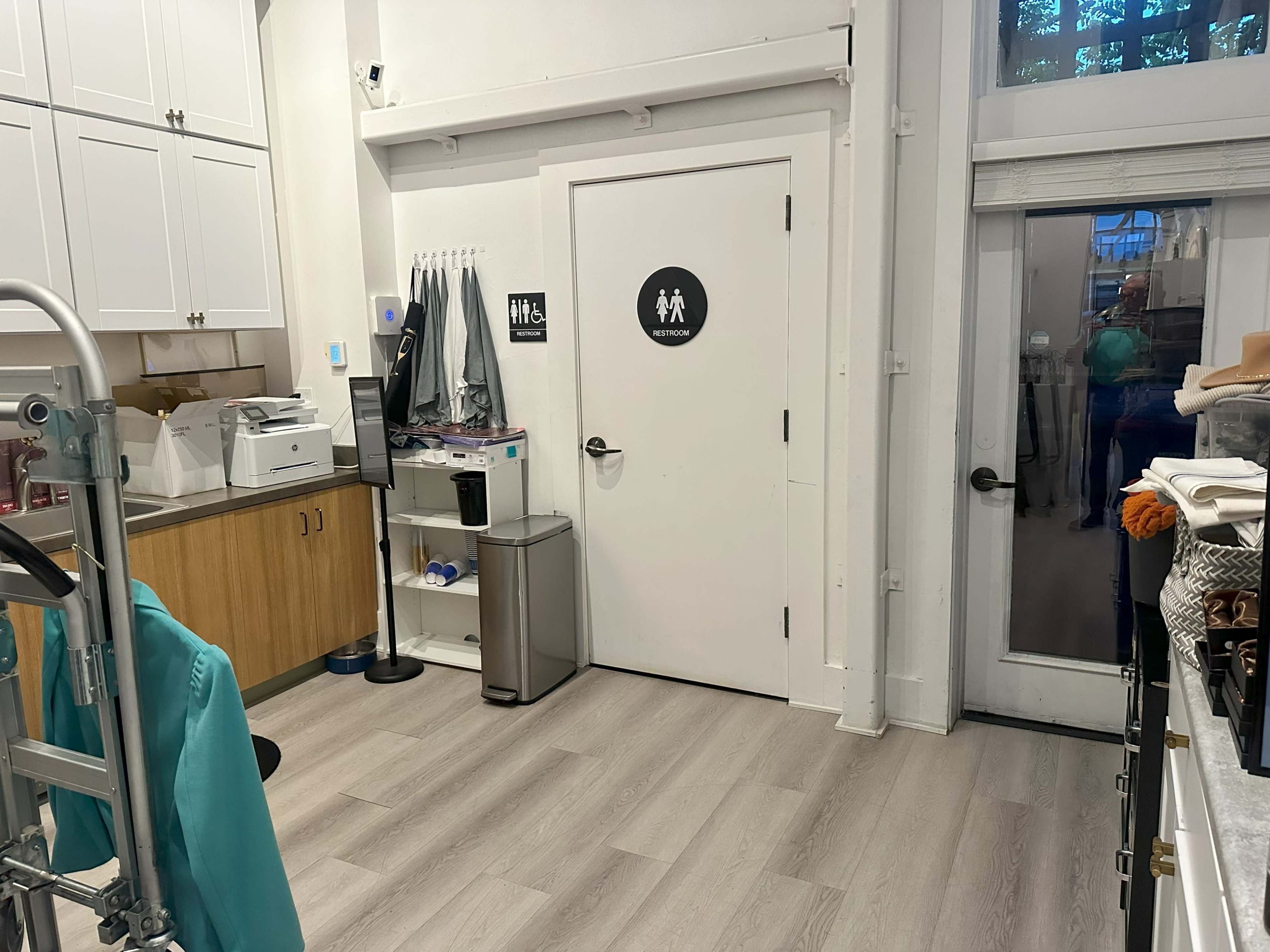 An interior space with a printer, trash can, and a door labeled for restroom access.