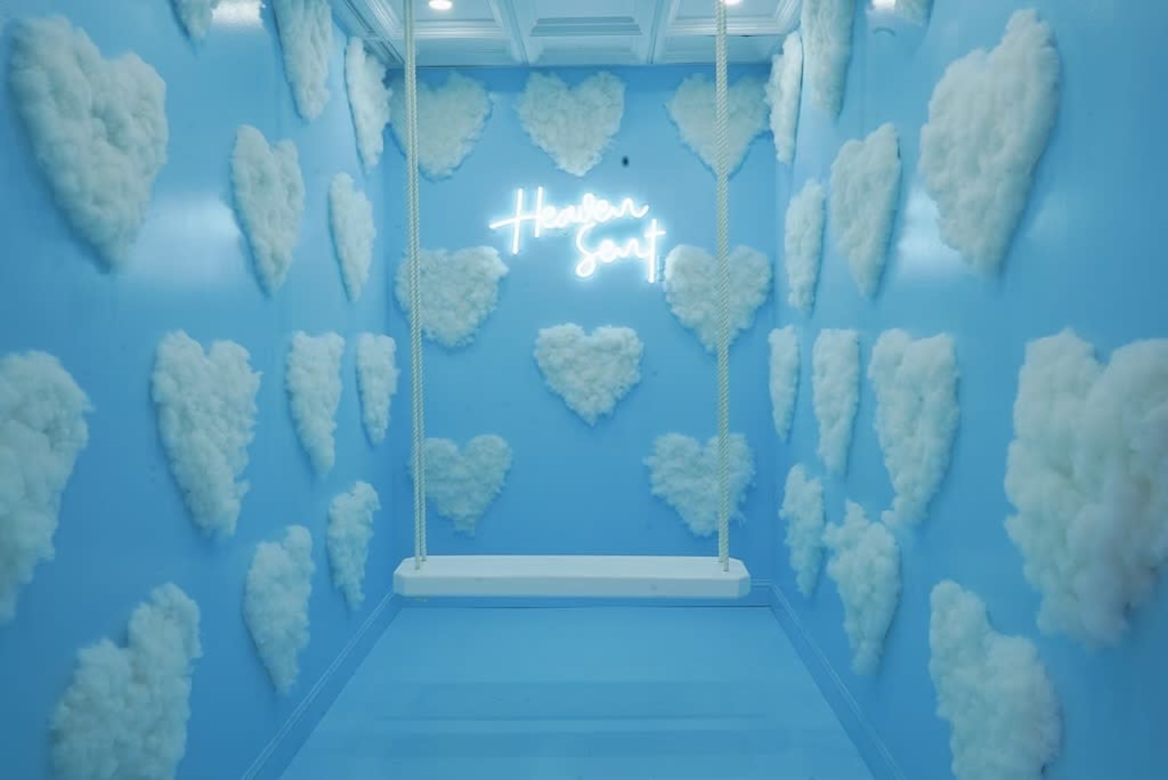 A blue room with heart-shaped cloud decorations on the walls and a swing hanging from the ceiling.