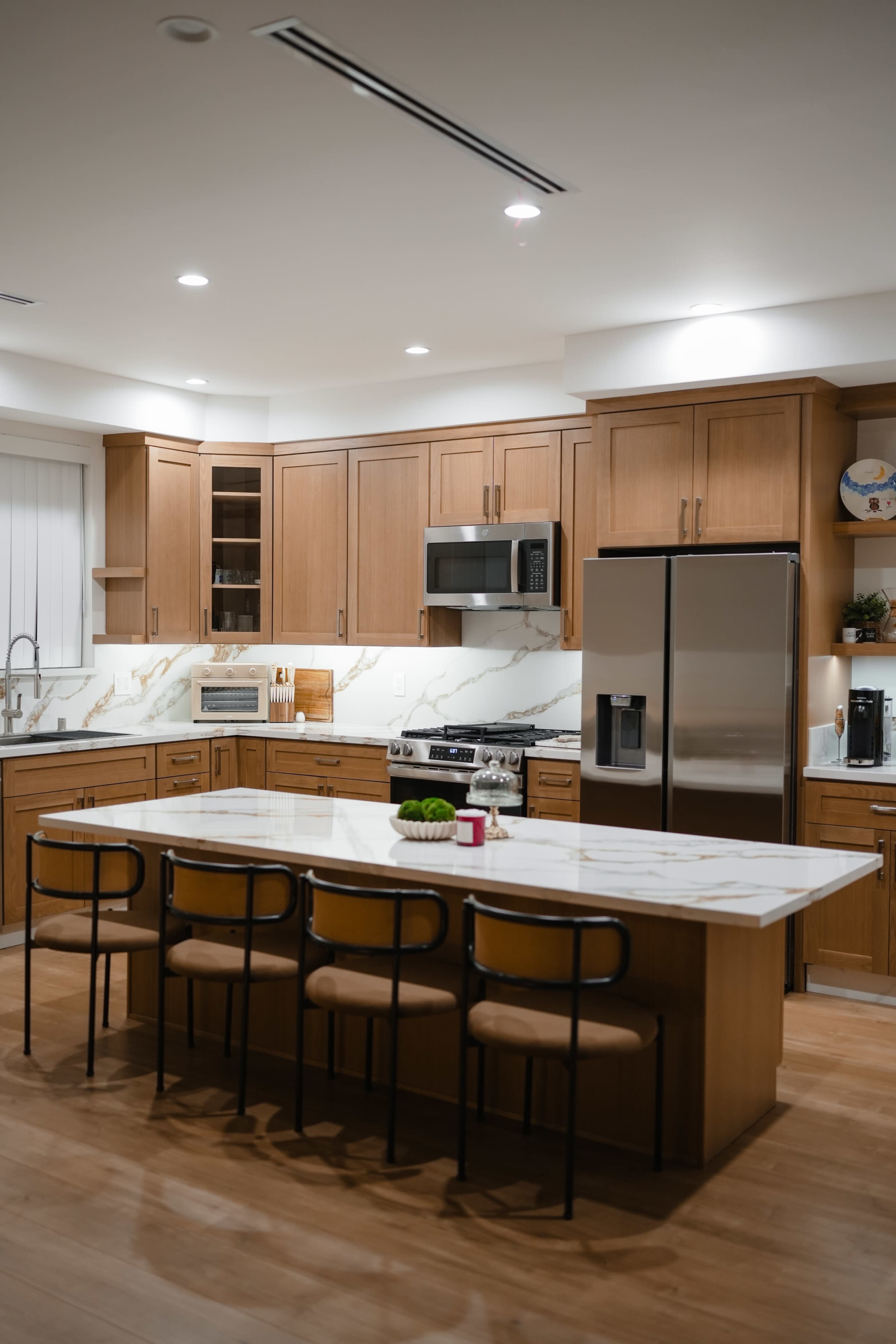 The kitchen features wooden cabinets, stainless steel appliances, and an island with seating for six.