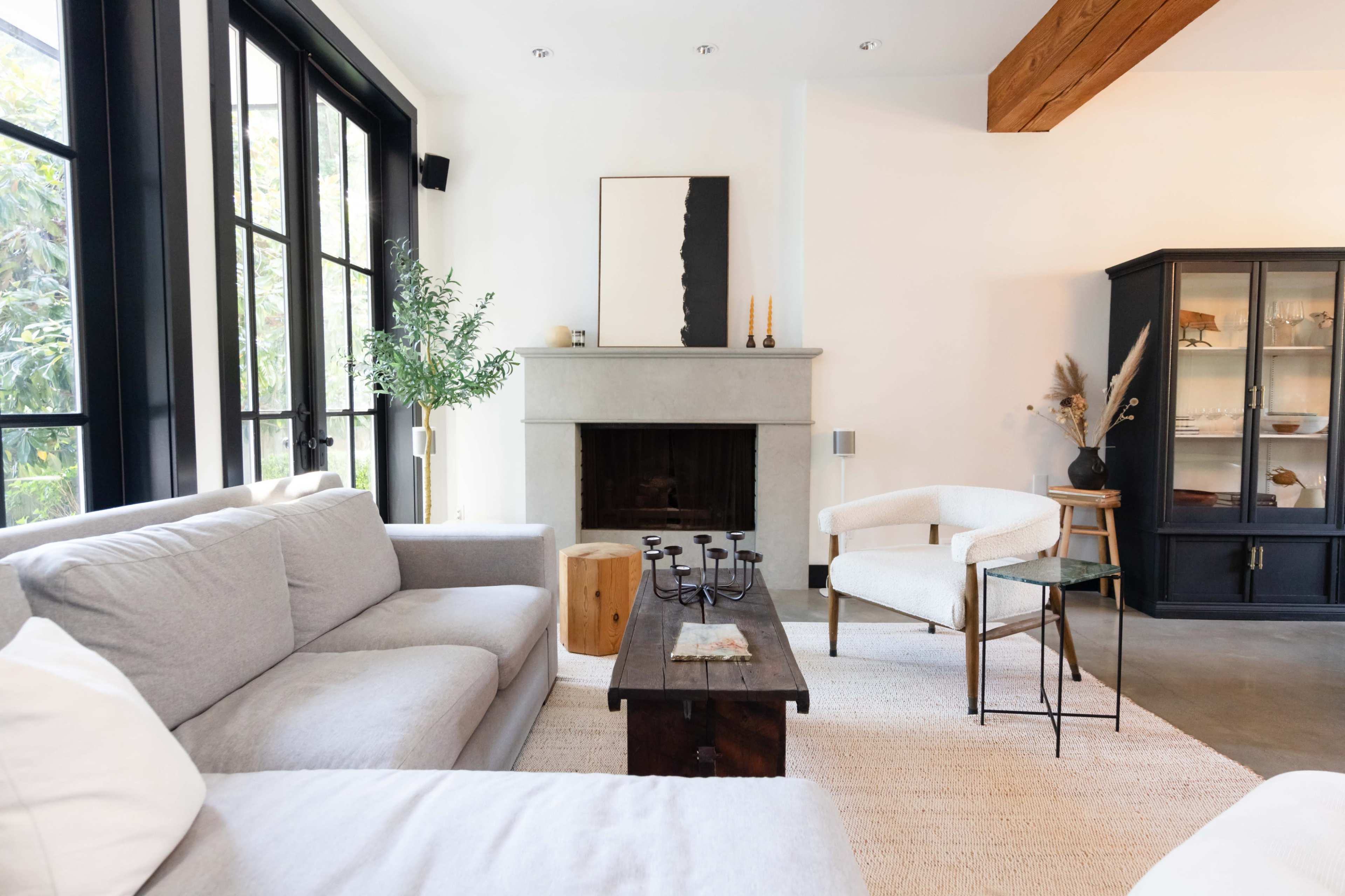 The living room features a gray sofa, a wooden coffee table, and a minimalist fireplace with a black framed cabinet against a white wall.